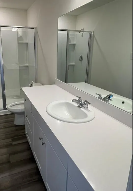 White vanity with an integrated sink, chrome faucet, and expansive wall-mounted mirror