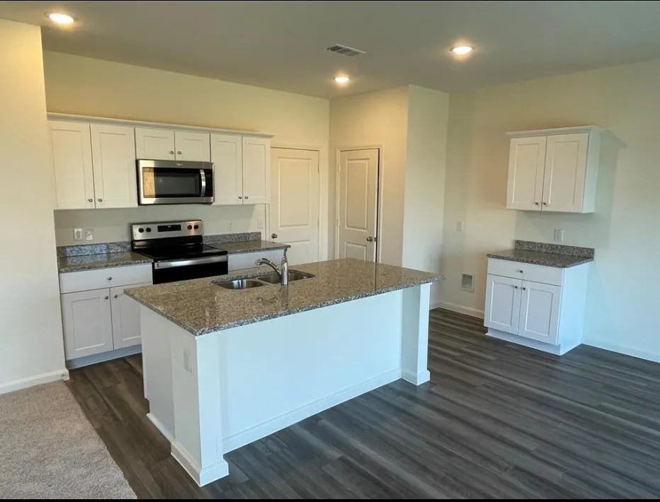 Kitchen featuring white cabinetry, stainless steel appliances, granite countertops, and wood-finish flooring