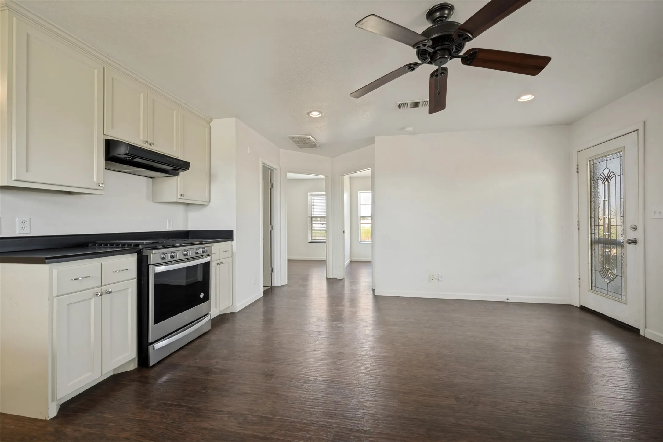 Kitchen with light cabinetry, dark countertops, and stainless steel range