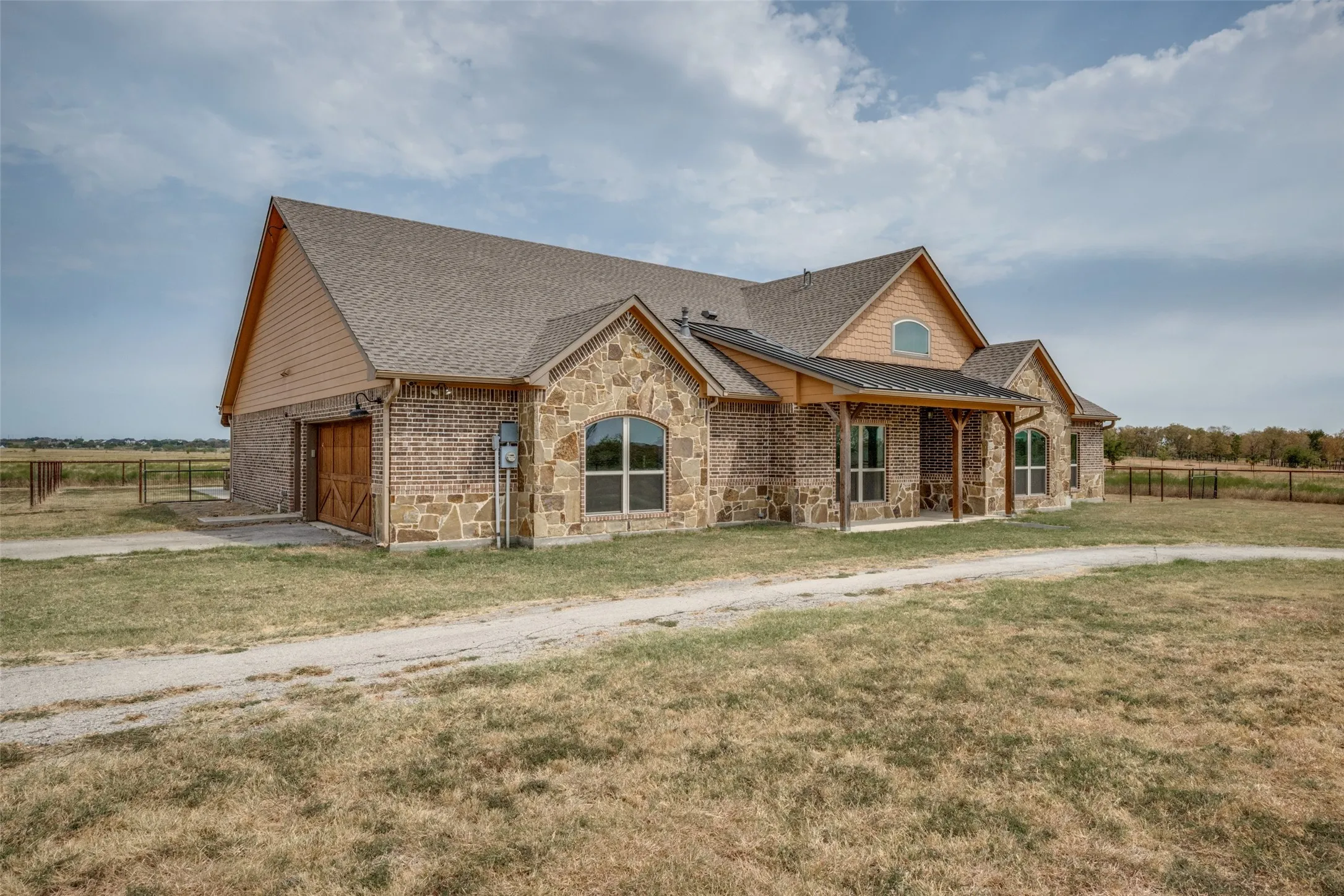 Stone and brick exterior with a covered front porch featuring wood posts