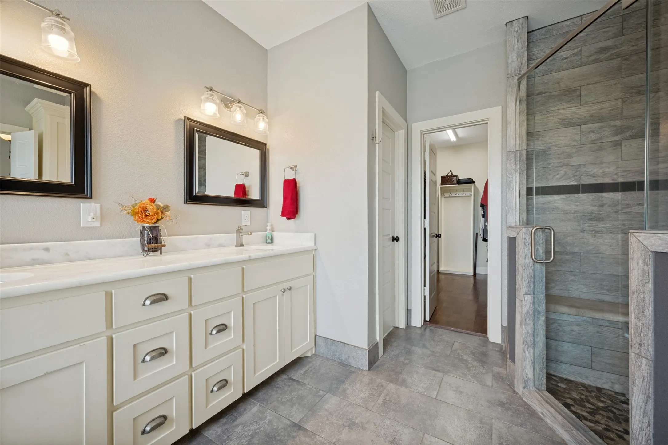 Primary bathroom with dual vanity with a white countertop and undermount sinks, framed mirrors, and chrome light fixtures