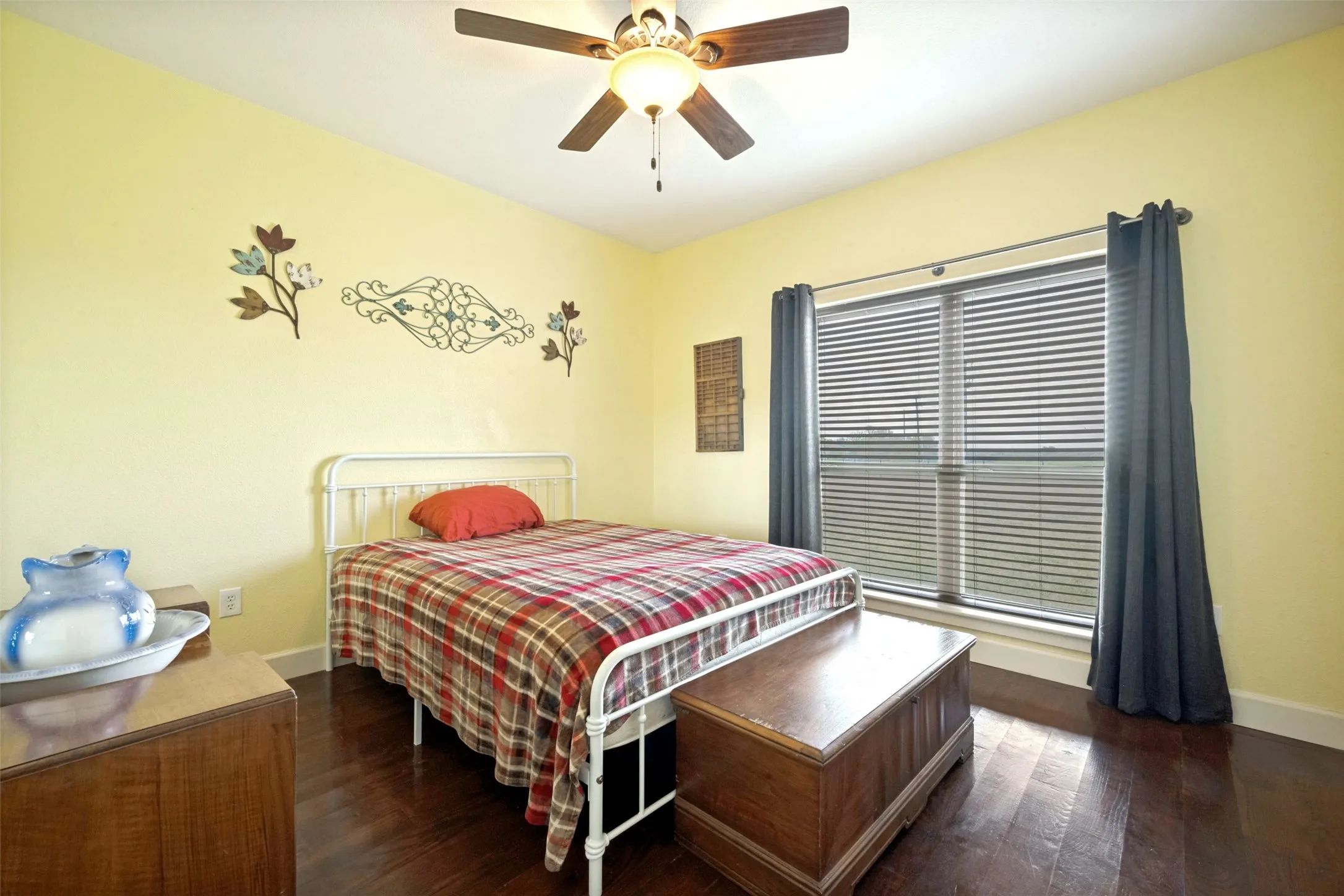 Yellow-painted walls, wood-finish flooring, and a ceiling fan with light fixture