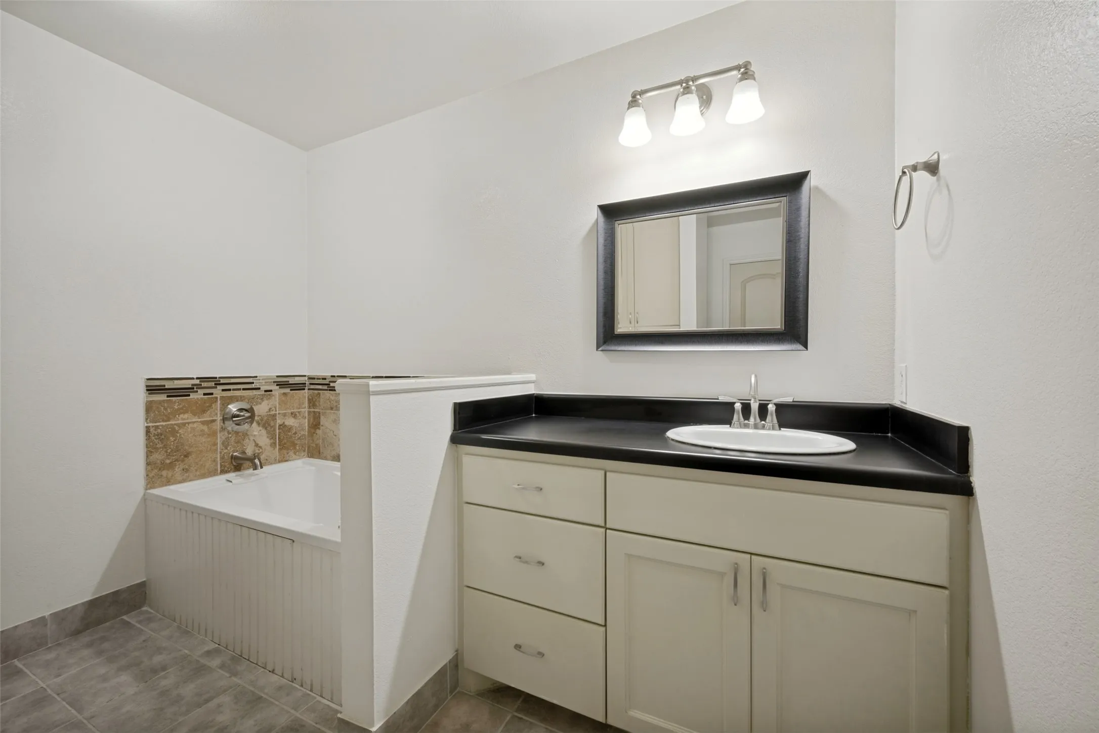 Vanity with integrated sink, dark countertop, and brushed nickel faucet