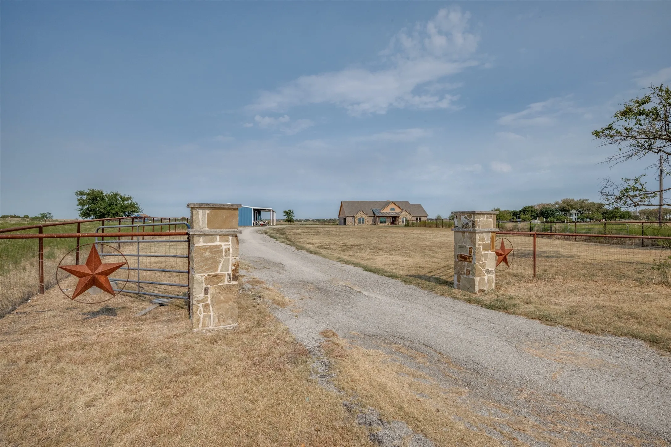 Gravel driveway leading to a stone exterior residence with a built-in garage