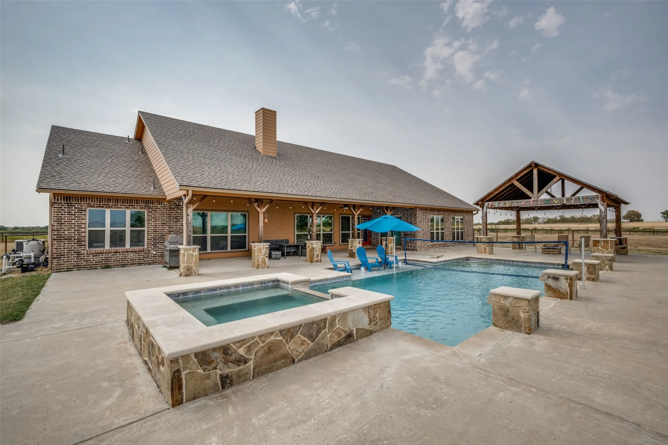 Expansive concrete patio featuring a built-in swimming pool and integrated spa