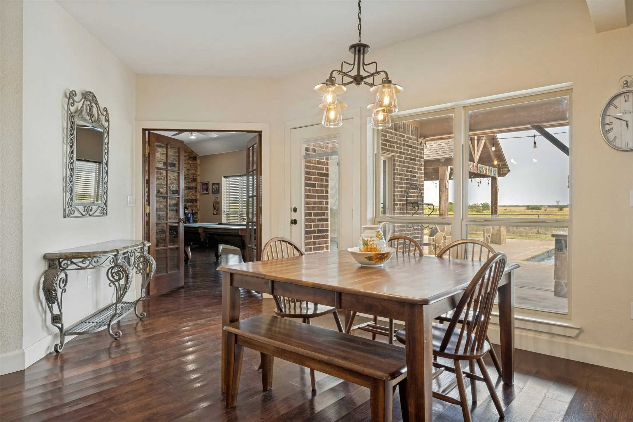 Wood-finish flooring, multi-pane windows, and a black iron chandelier with glass shades