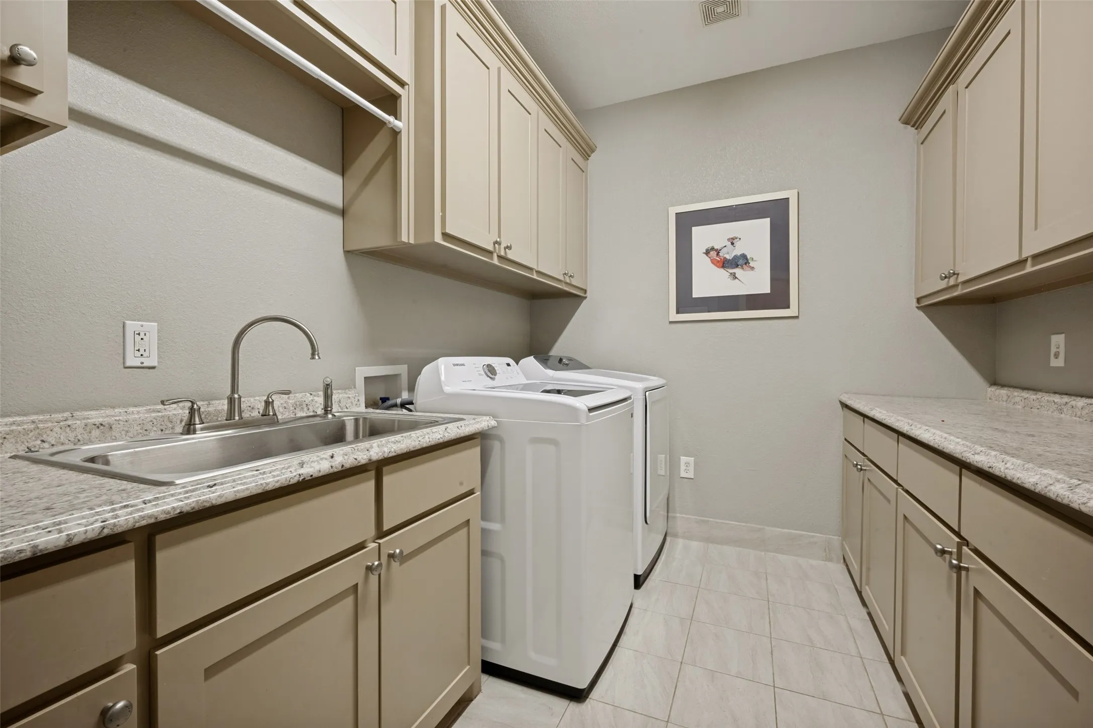 Laundry room featuring extensive cabinetry, a stainless steel utility sink, composite countertops, and tile flooring