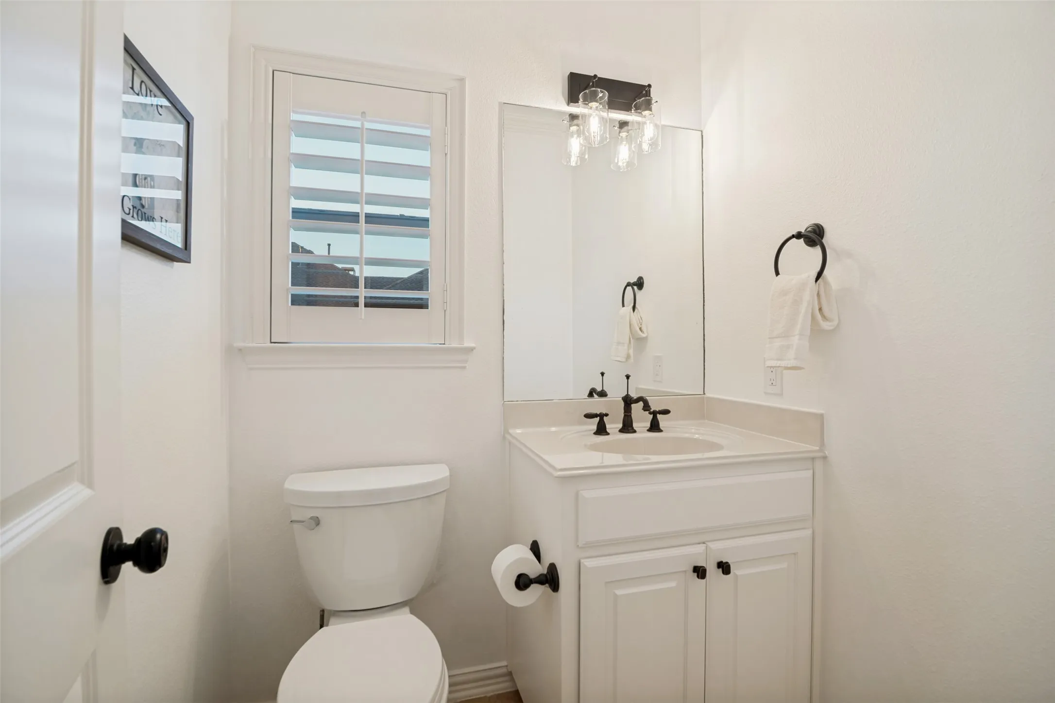 White shaker-style vanity with a light-toned countertop, rectangular undermount sink, and dark-finish faucet