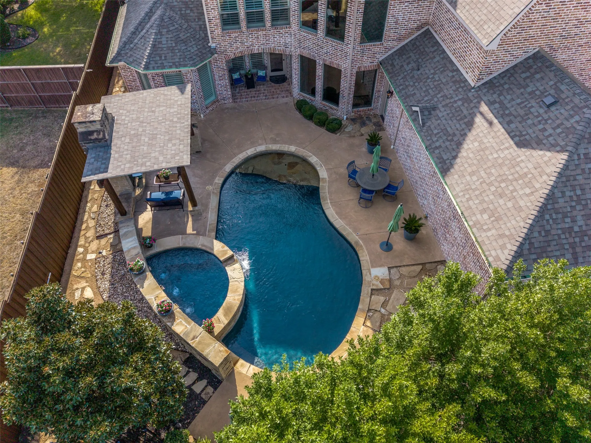 Freeform swimming pool with integrated spa, stone coping, and concrete decking