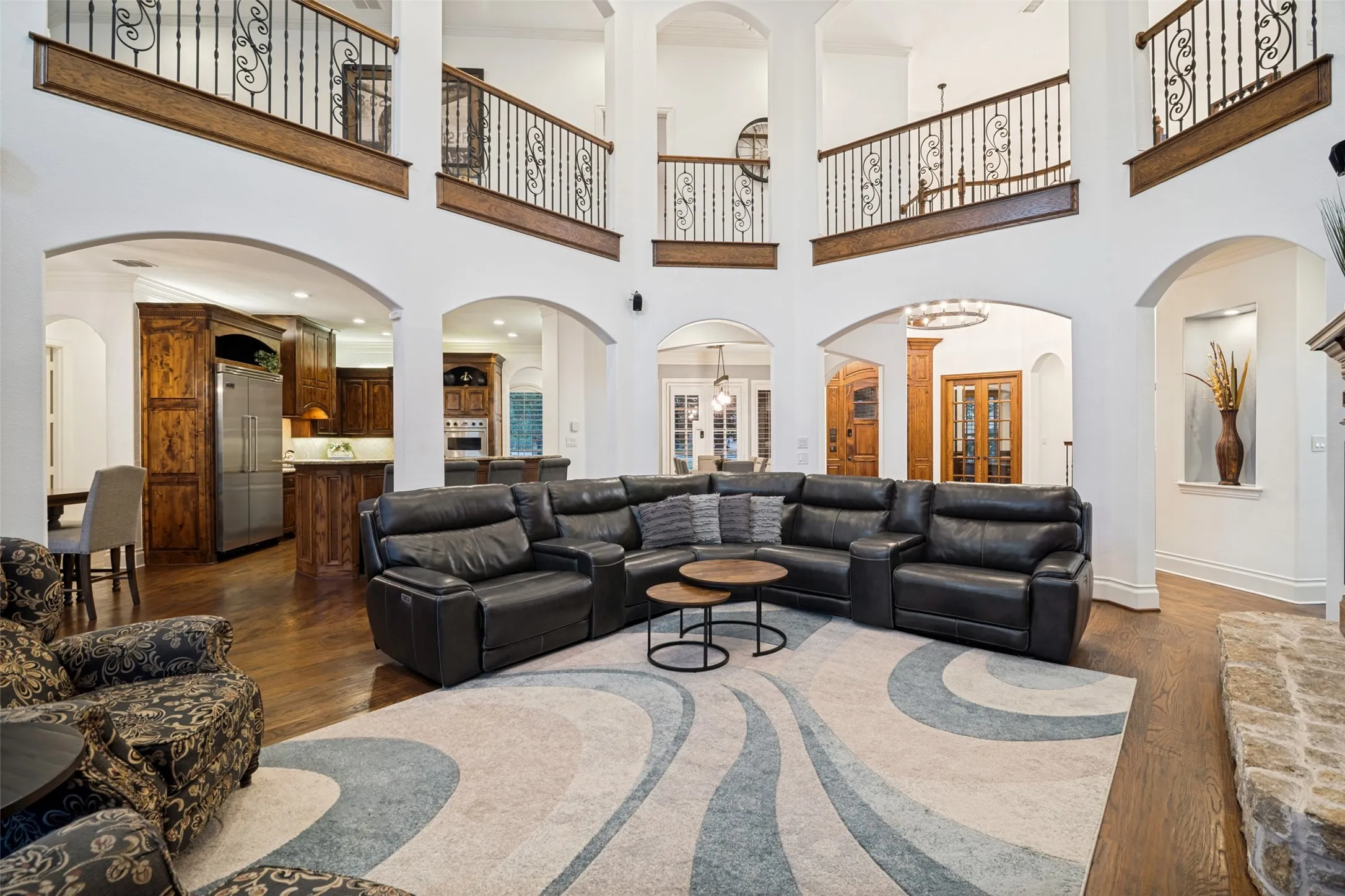 Two-story interior with arched doorways, dark wood-finish flooring, and upper-level railings with decorative iron balusters