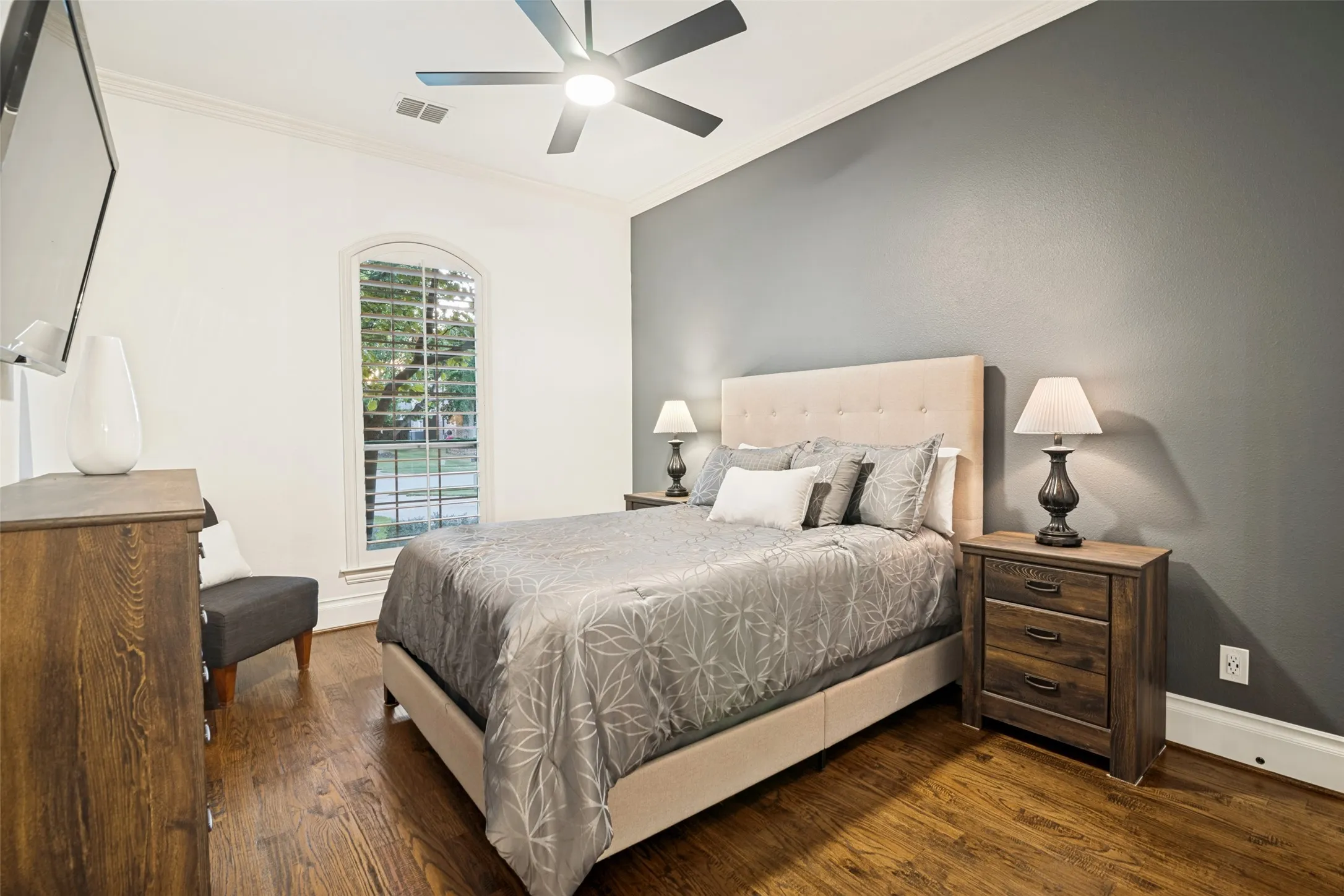 Second Primary with ensuite bathroom - Arched window with plantation shutters, wood-finish flooring, ceiling fan, and crown molding