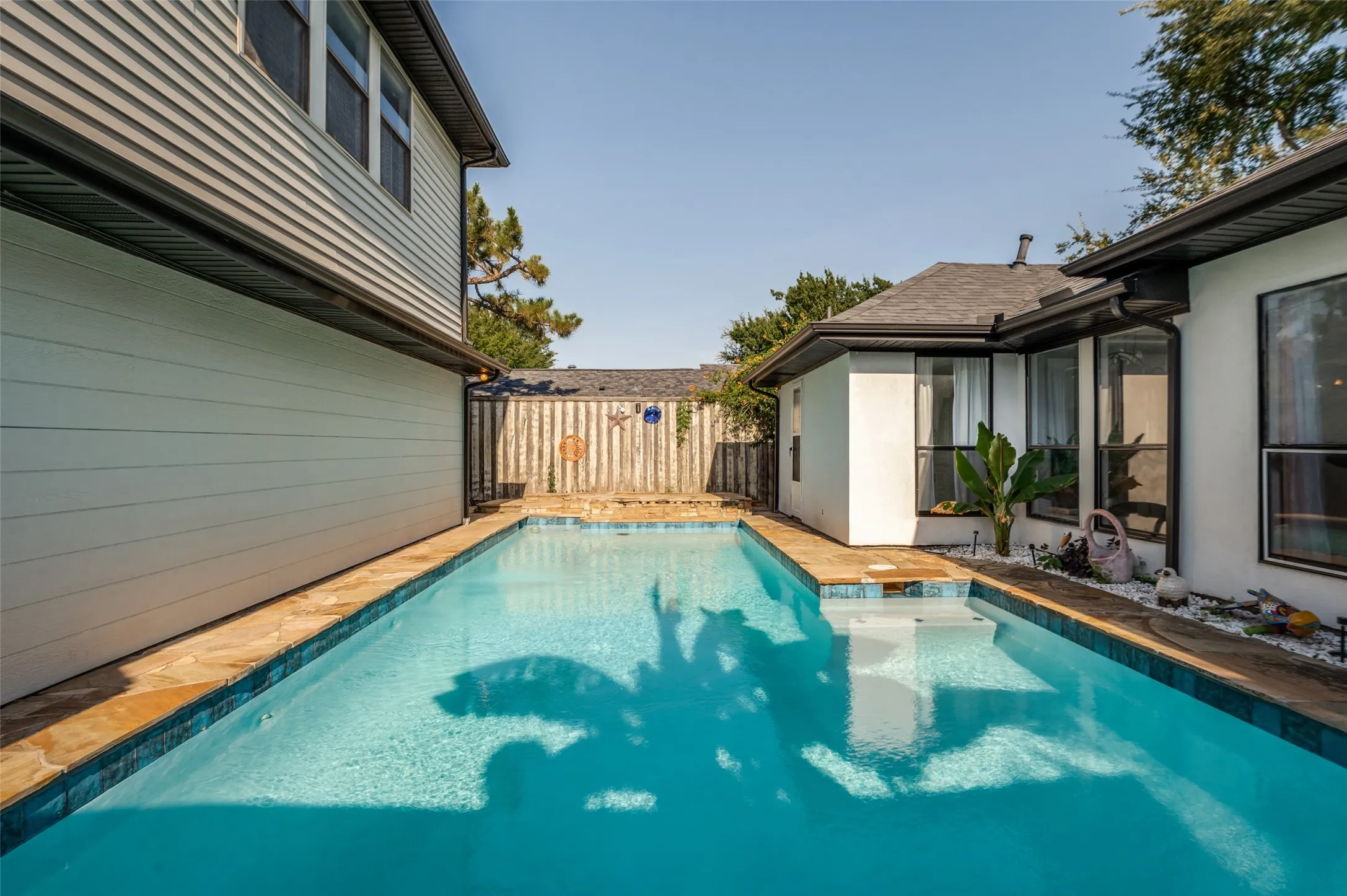 In-ground swimming pool with integrated steps, surrounded by flagstone coping