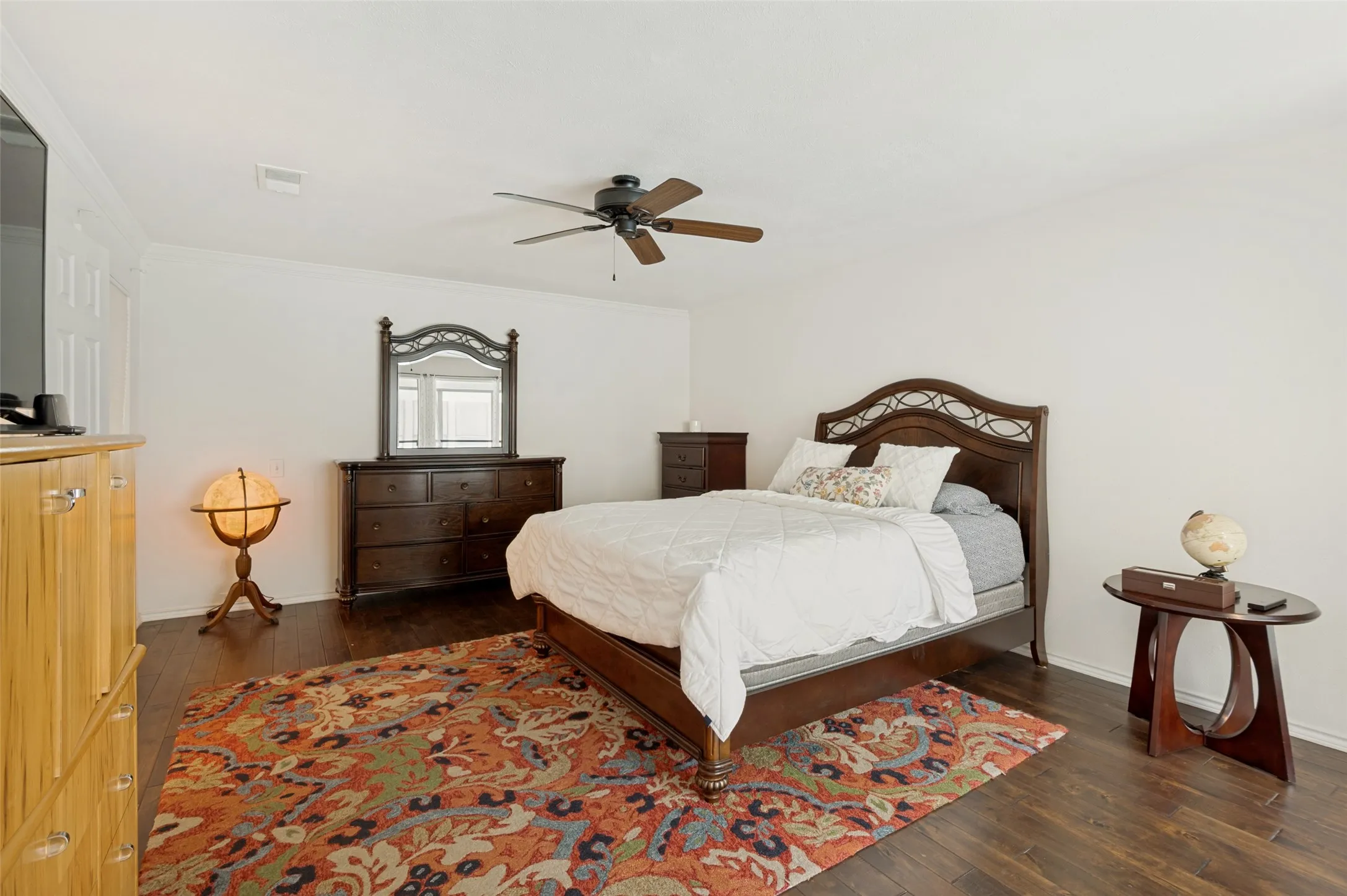 Master bedroom featuring dark wood-finish flooring, ceiling fan fixture, white walls, and white trim