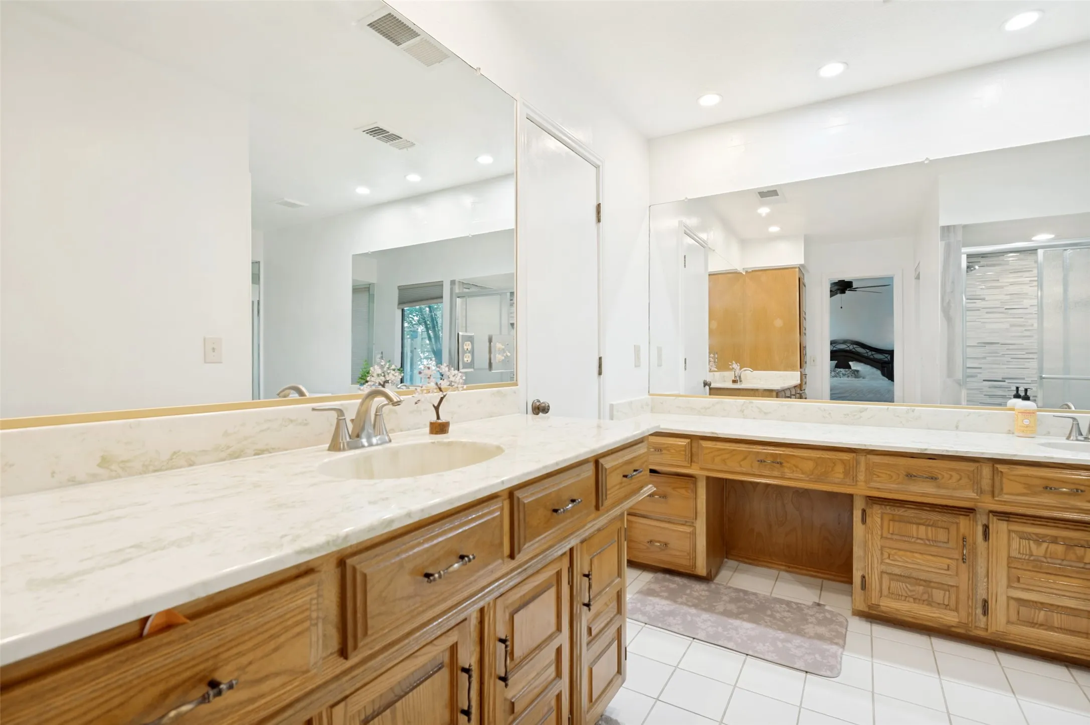 Master bathroom featuring a dual vanity with integrated sinks, light-toned countertops, and wood-finish cabinetry