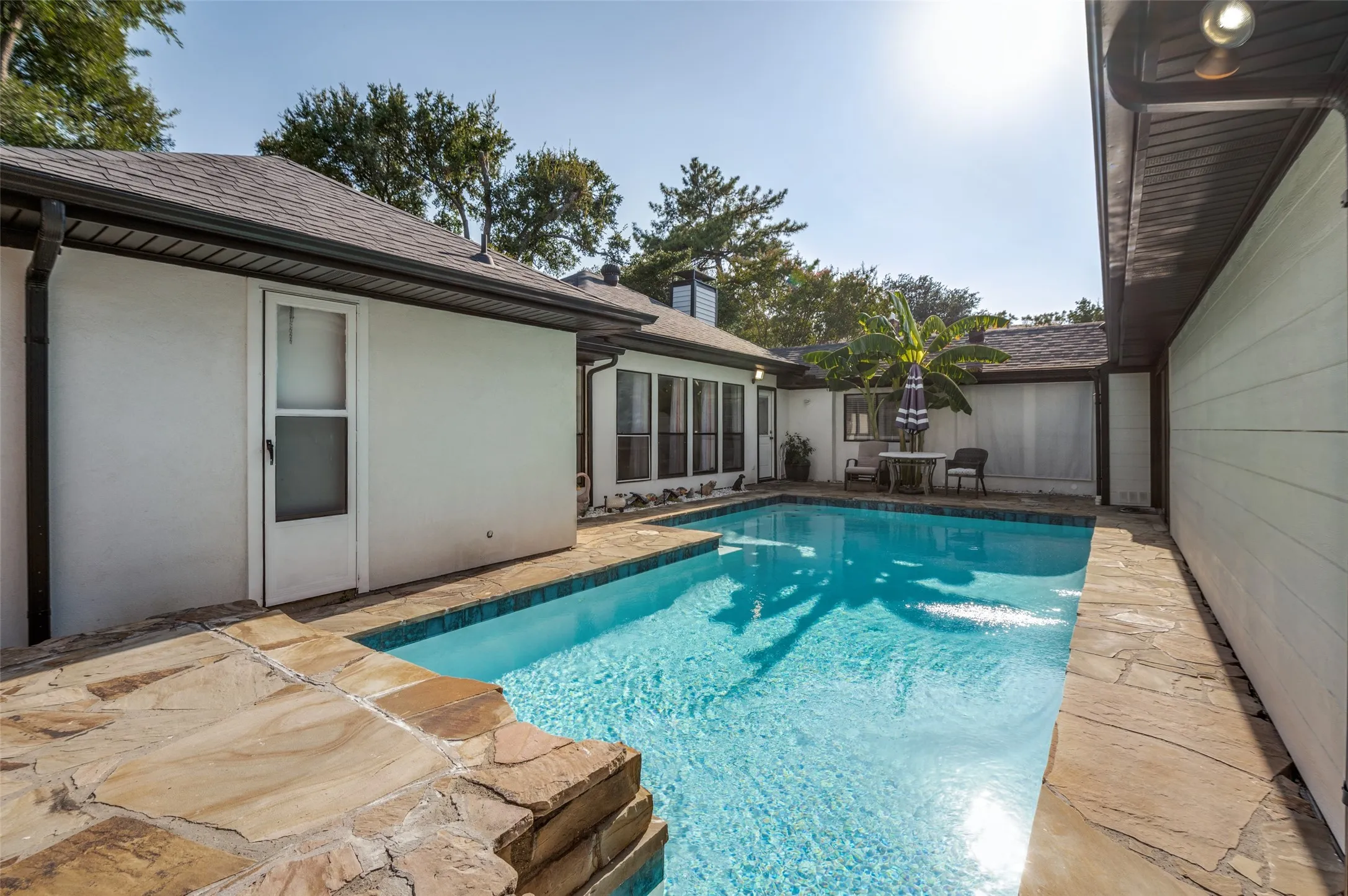 Outdoor swimming pool with integrated stone coping and surrounding flagstone patio