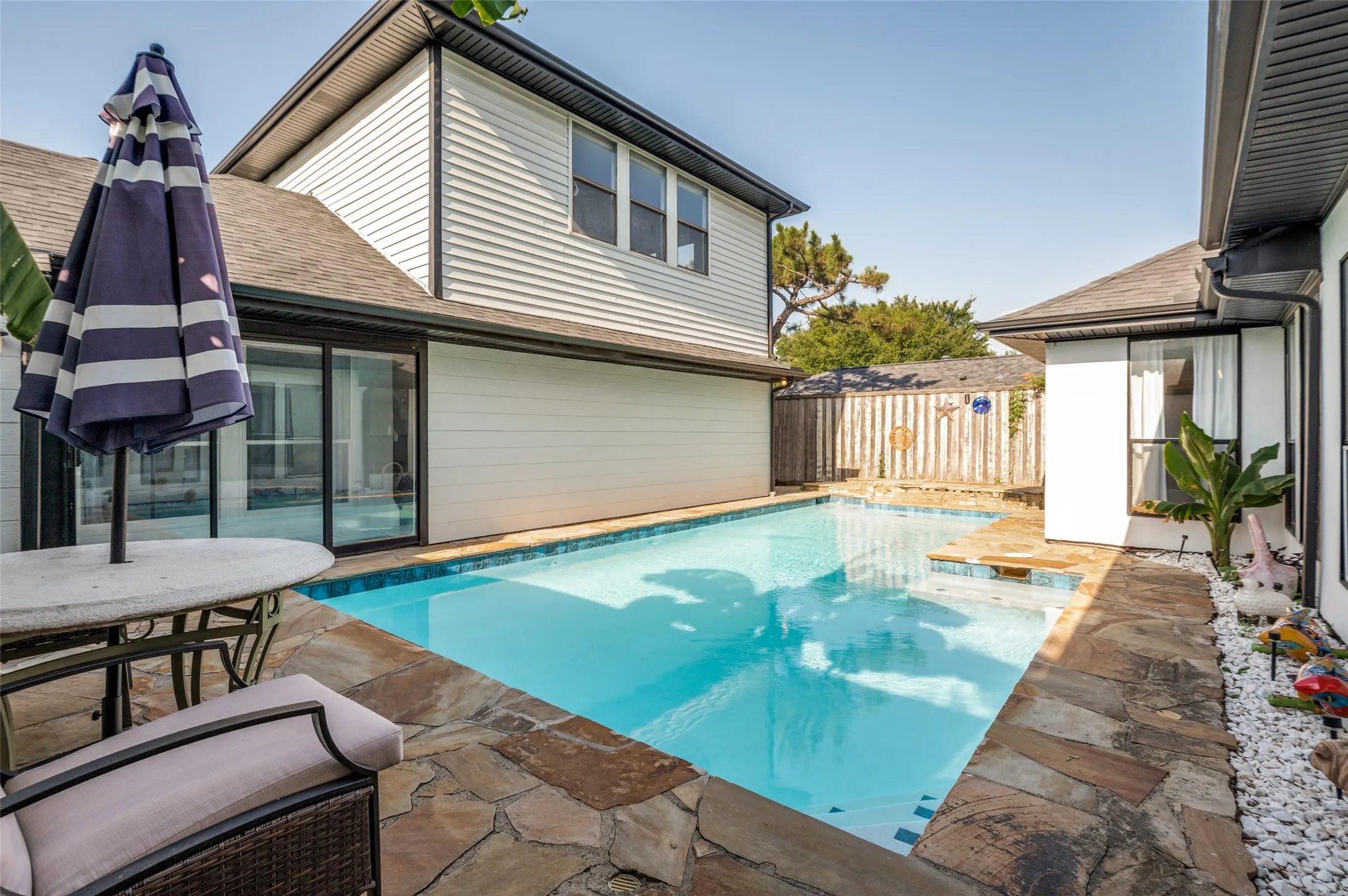 Private backyard oasis featuring a rectangular pool with integrated spa and stone coping.