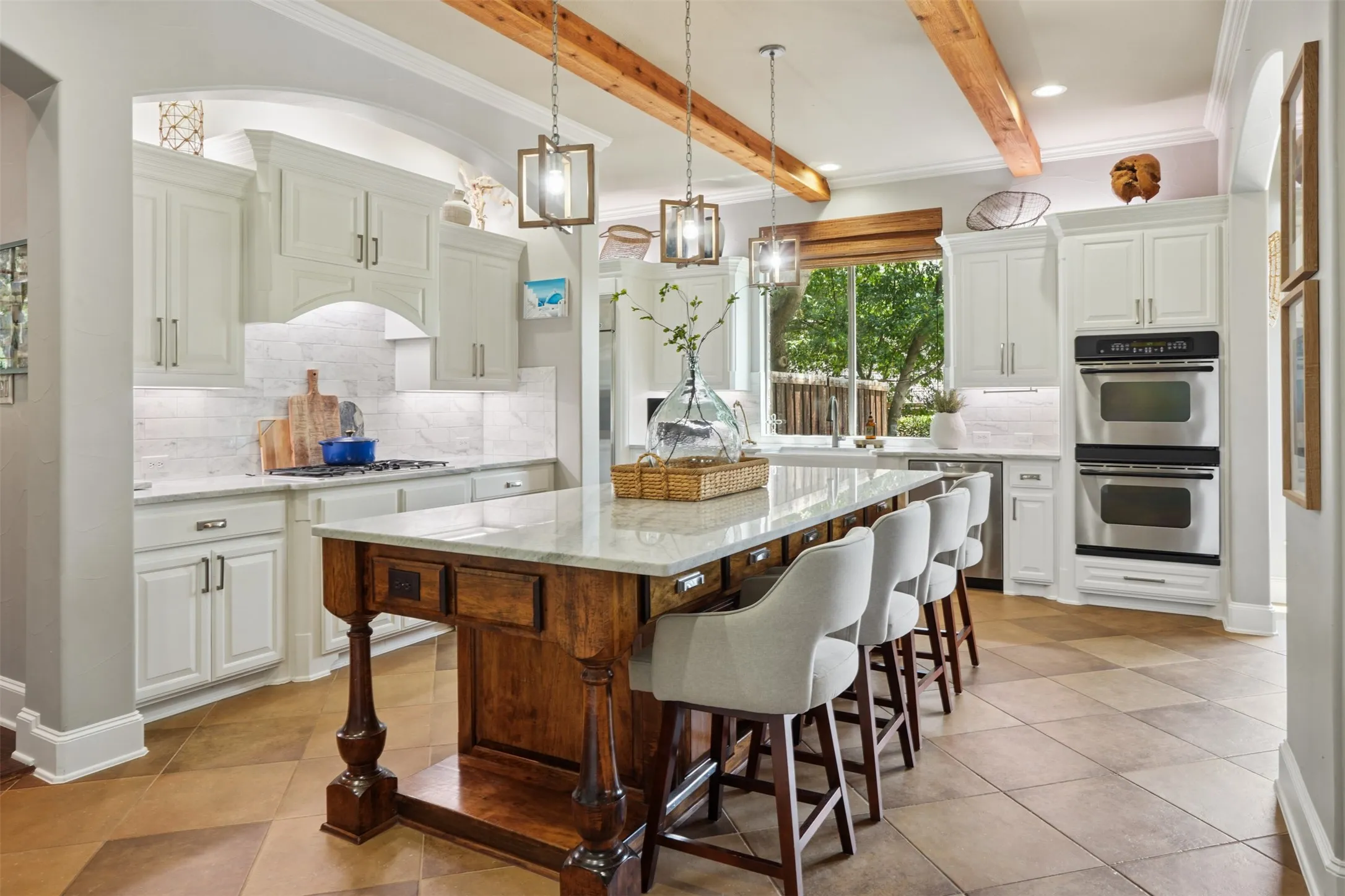 Custom carved island anchors the remodeled kitchen beneath warm rough-finish pine ceiling beams.