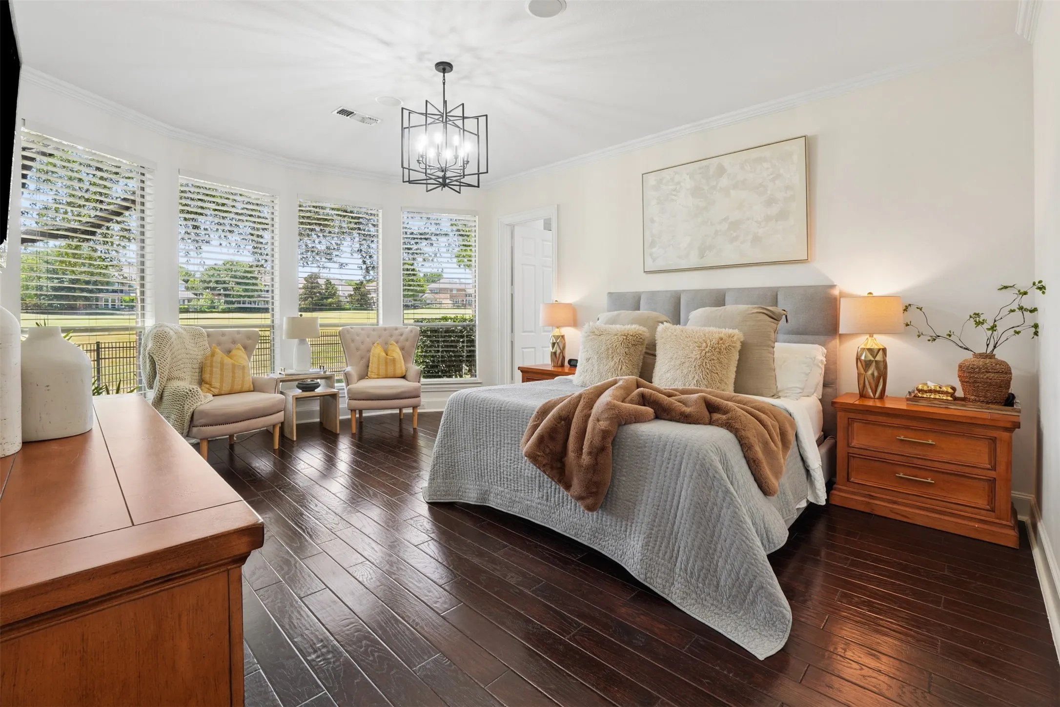 Spacious downstairs primary suite offers hardwood floors and a peaceful view toward the backyard.