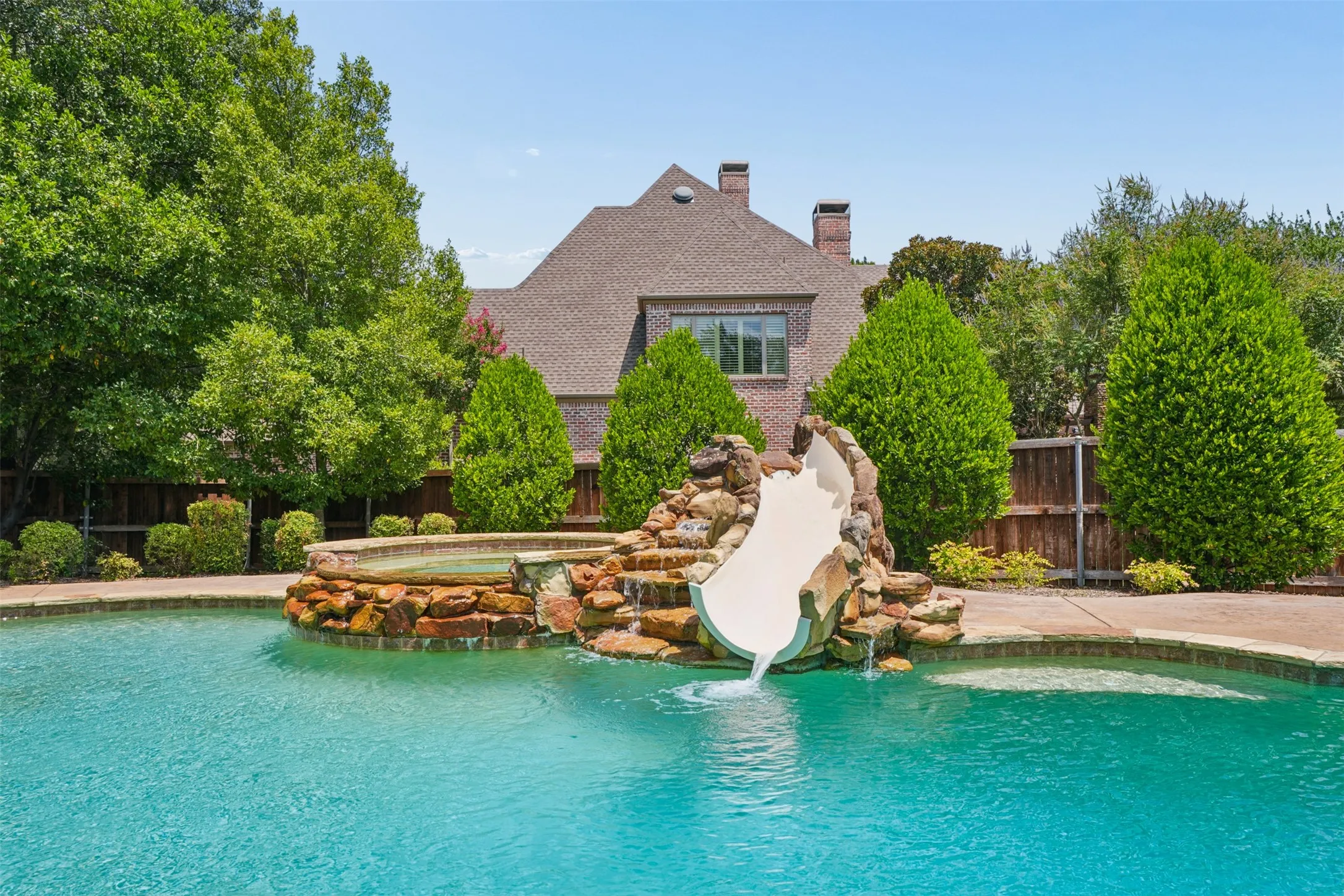 Resort-style pool features a dramatic rock-integrated waterslide, spa and mature landscaping.