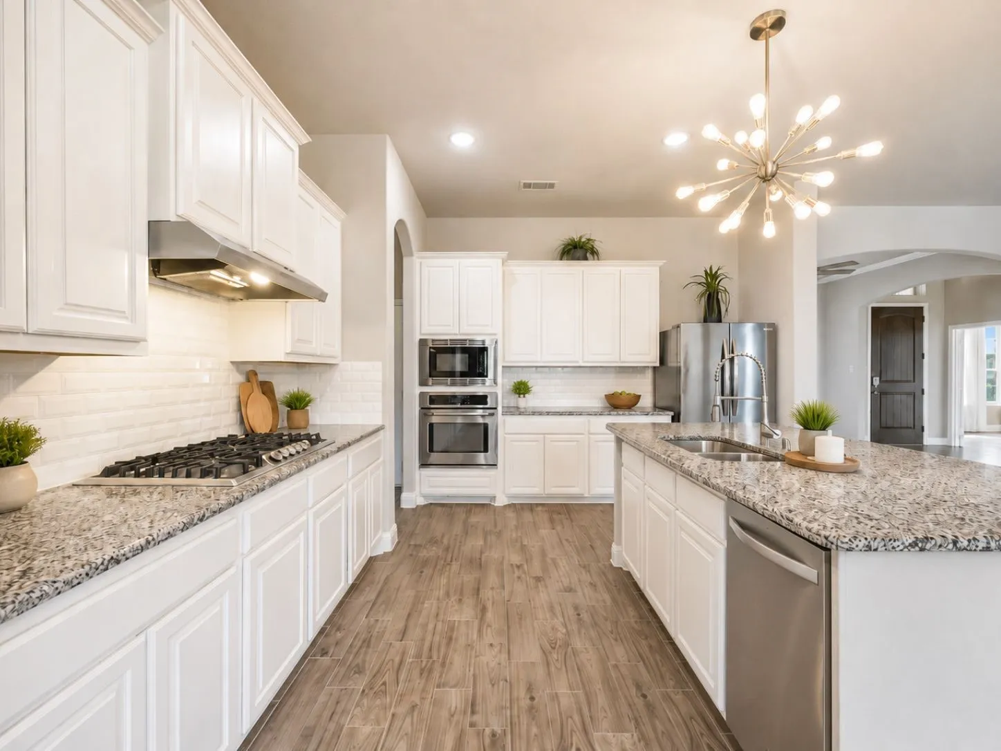 Kitchen featuring white cabinetry, granite countertops, stainless steel appliances, wood-finish flooring, and a decorative light fixture