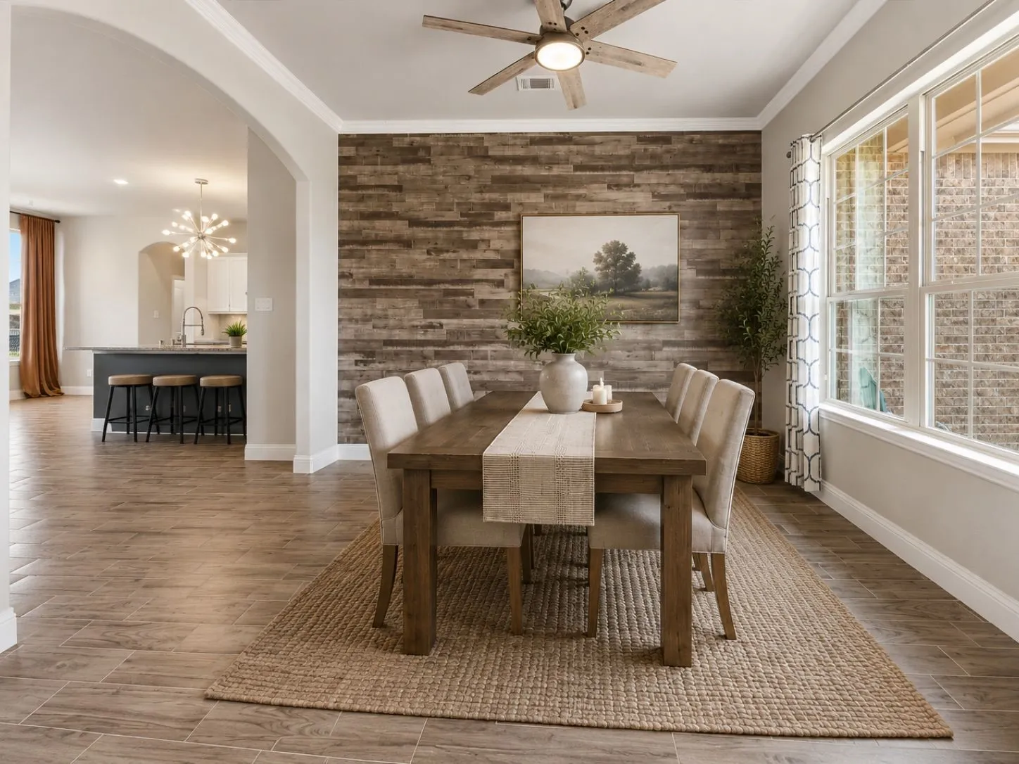 Wood-look plank tile flooring throughout, accent wall featuring horizontal wood paneling, arched doorway, and multi-pane windows