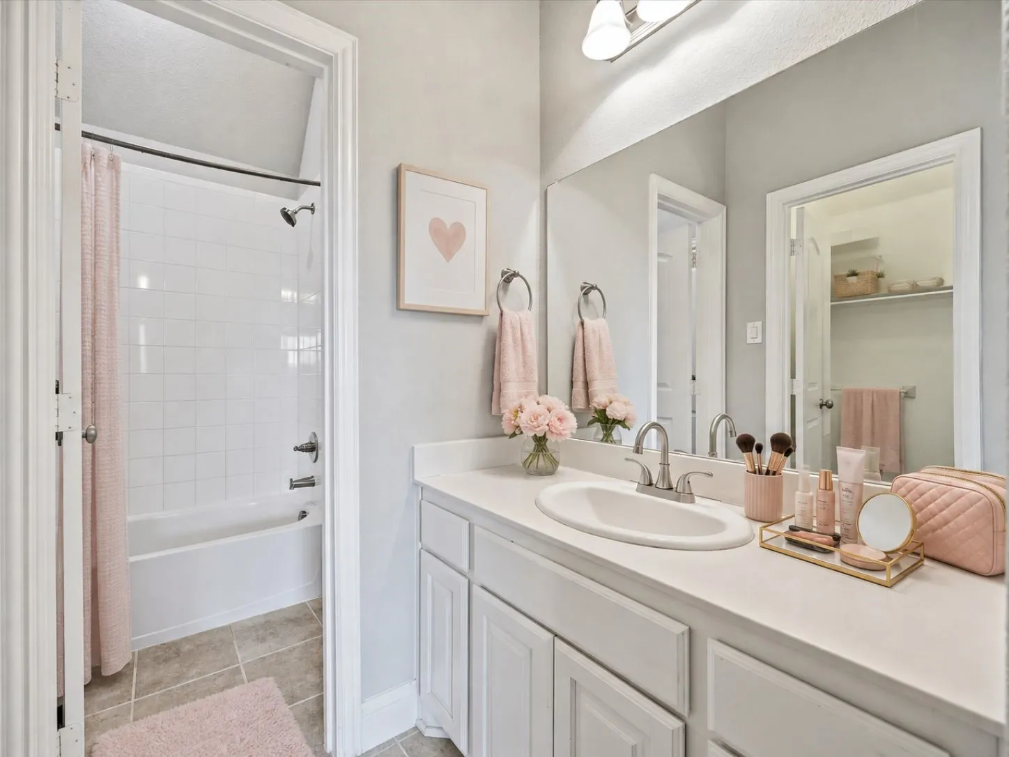 Vanity with a single sink and brushed nickel faucet, large wall mirror, white cabinetry, integrated tub and shower with white subway tile surround, and neutral tile flooring