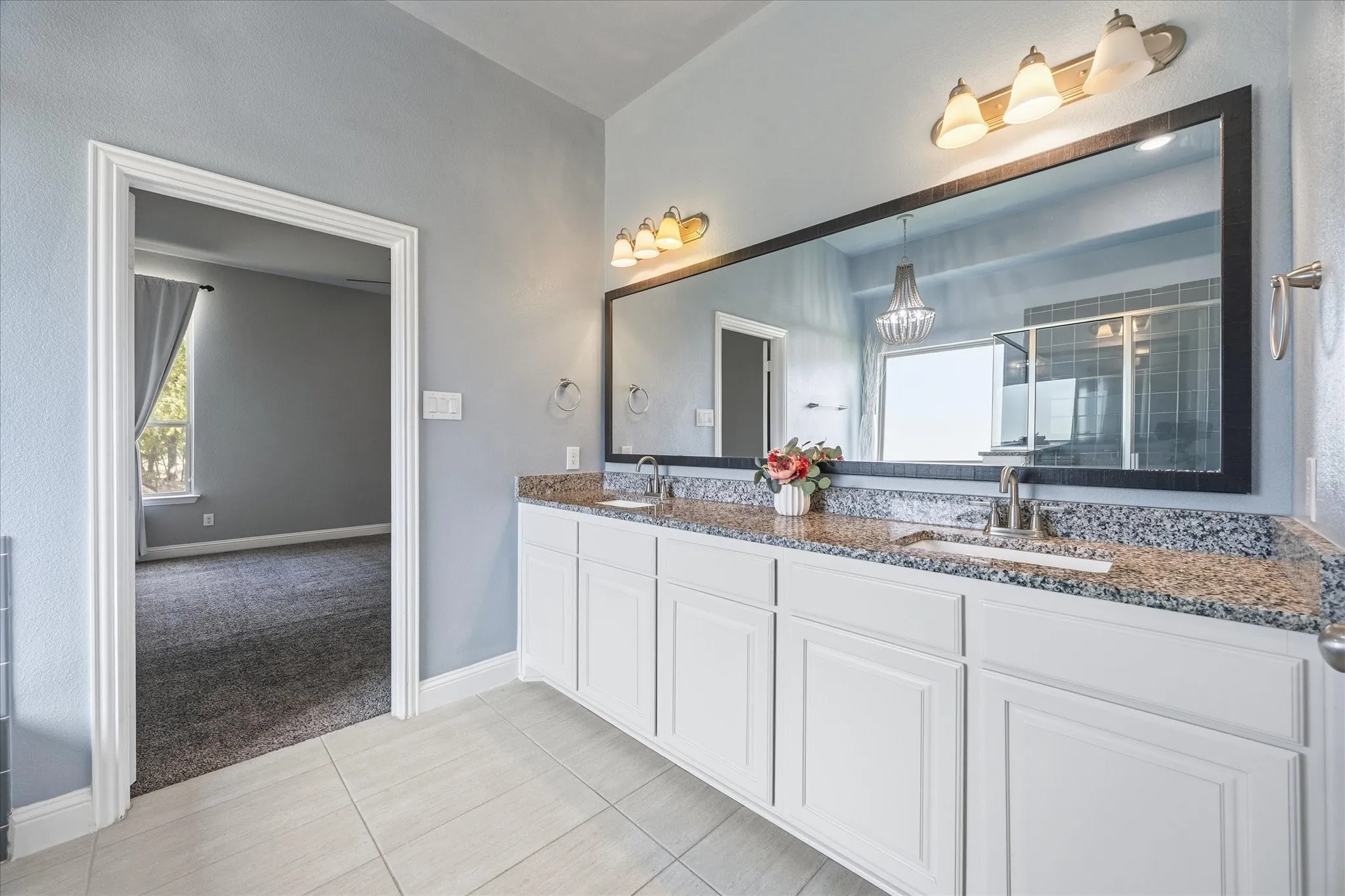 Dual vanity with white cabinetry, granite-finish countertop, and undermount sinks