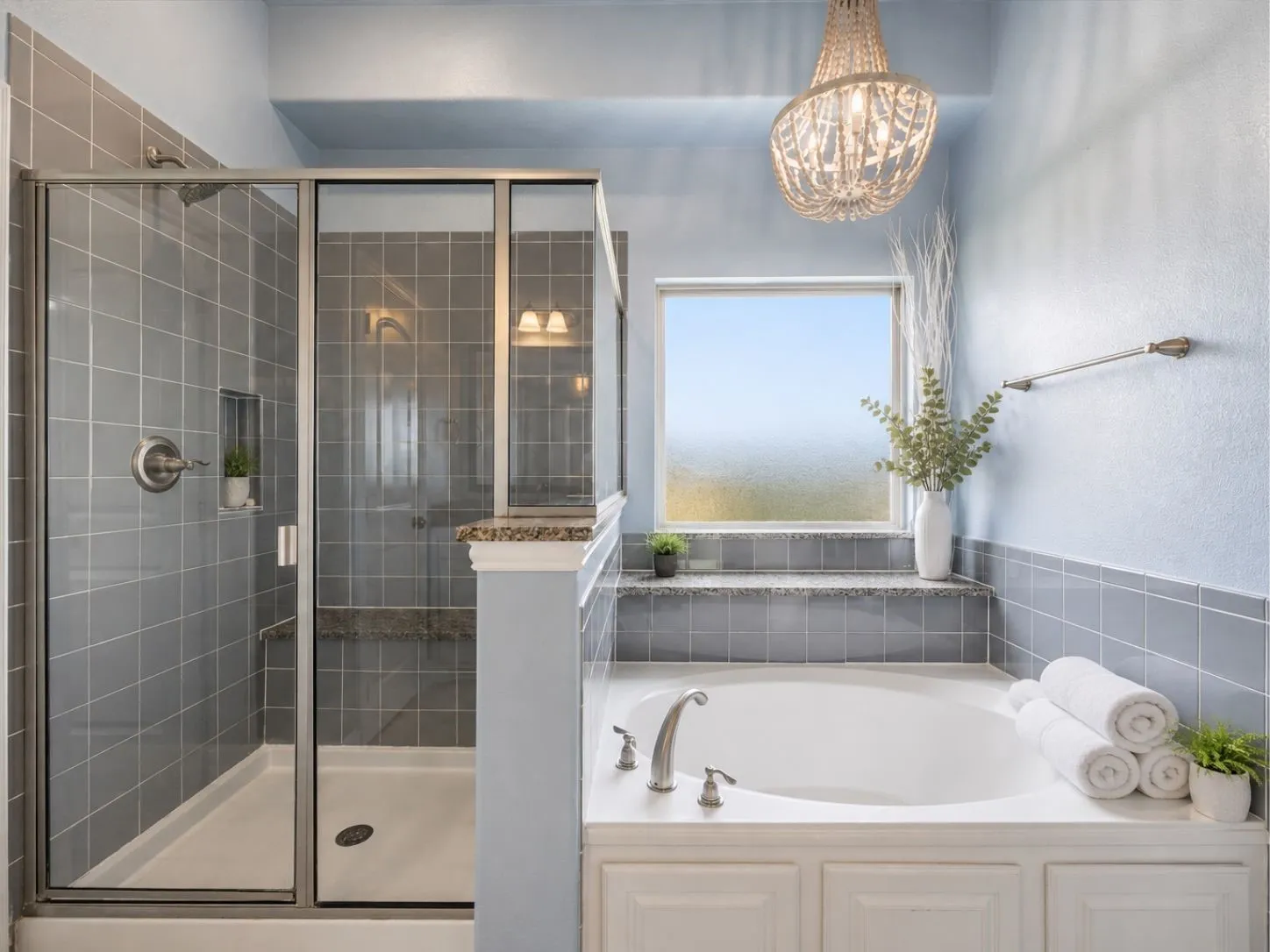 Built-in soaking tub, separate shower with glass enclosure, tiled walls, frosted window, and a decorative light fixture