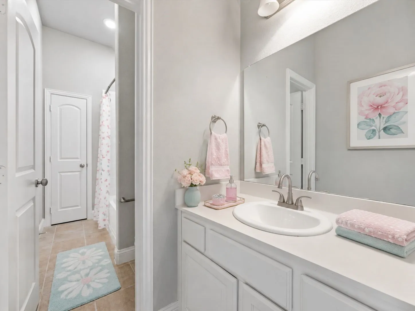 White vanity with integrated sink, brushed nickel faucet, large wall-mounted mirror, and tile flooring
