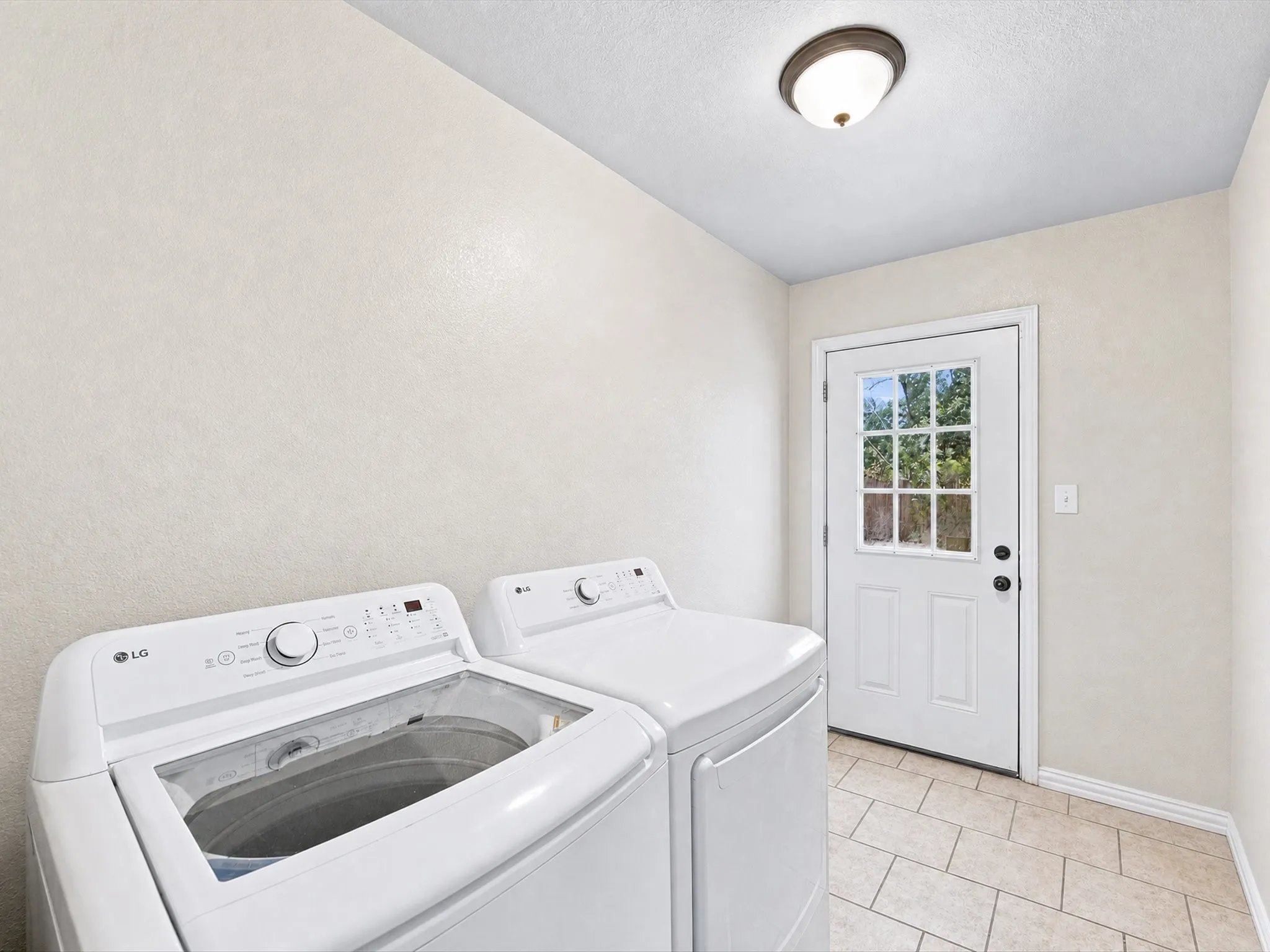 Laundry area with tiled flooring, neutral wall finish, and a ceiling-mounted light fixture