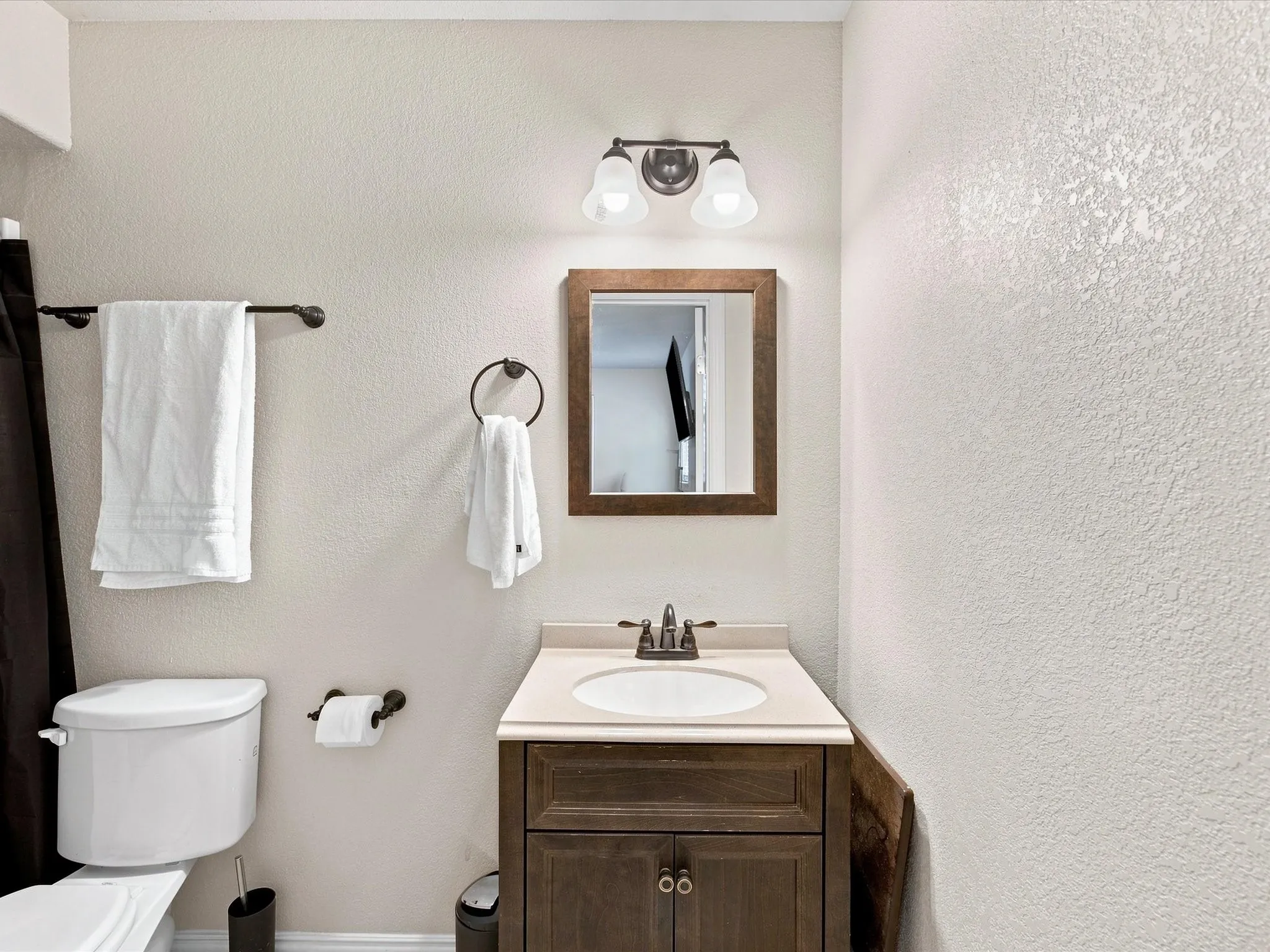 Vanity with a wood-finish cabinet, integrated sink, and an oil-rubbed bronze faucet