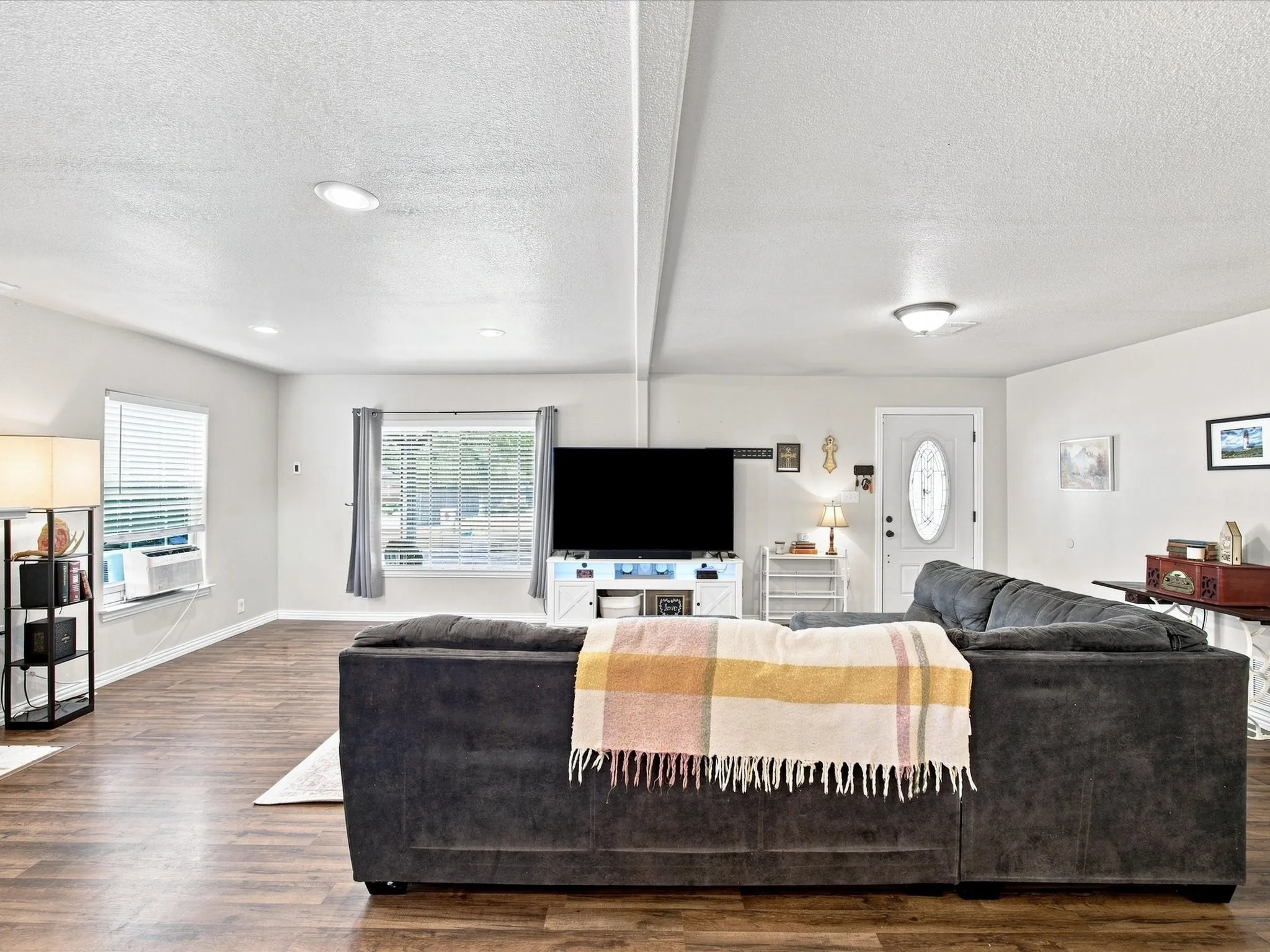 Recessed ceiling lighting, wood-finish flooring, multiple windows, and a front door with an oval-shaped decorative glass insert