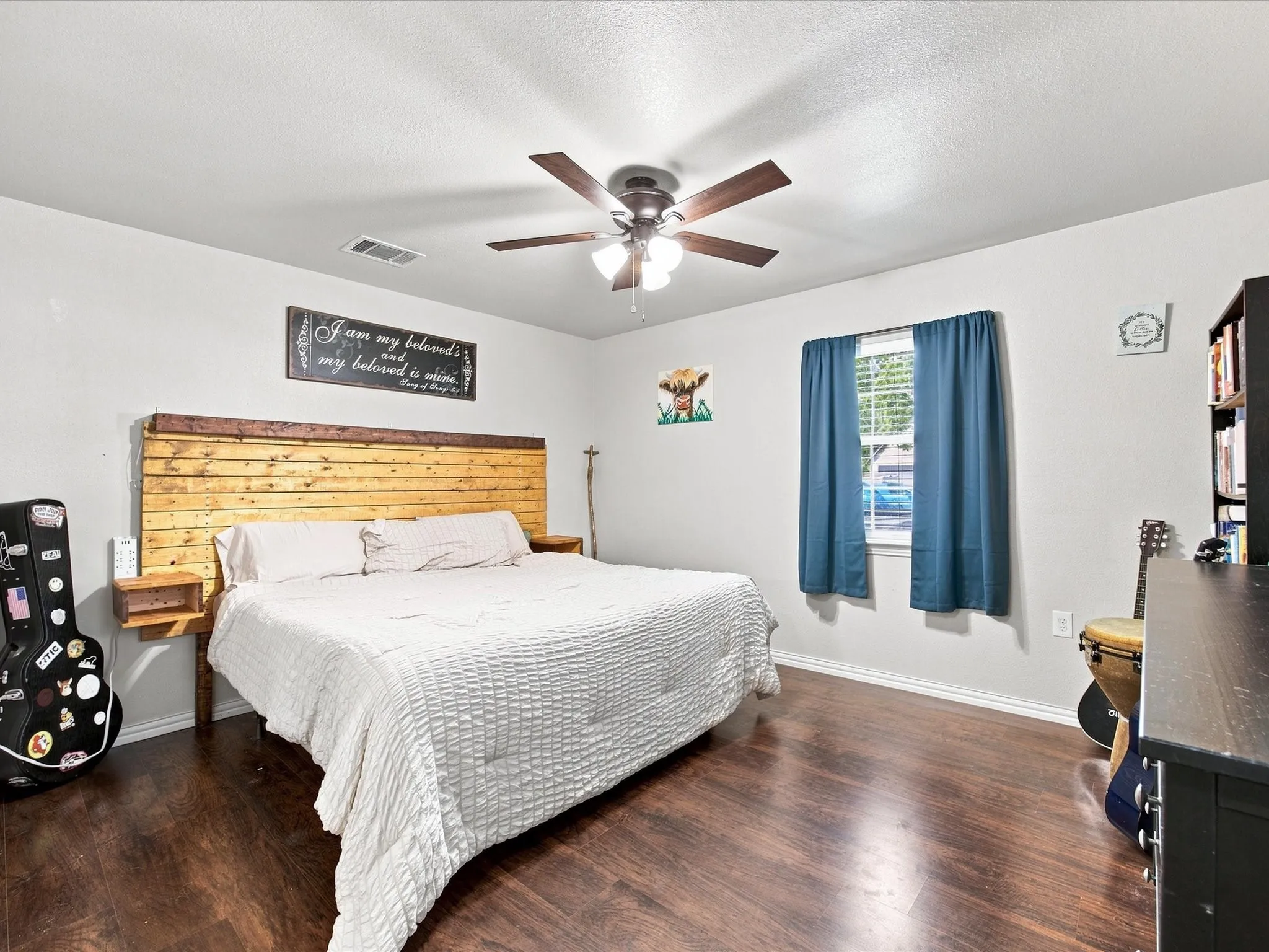 Wood-finish flooring, ceiling fan with integrated lighting, window with blinds, and light-toned wall paint