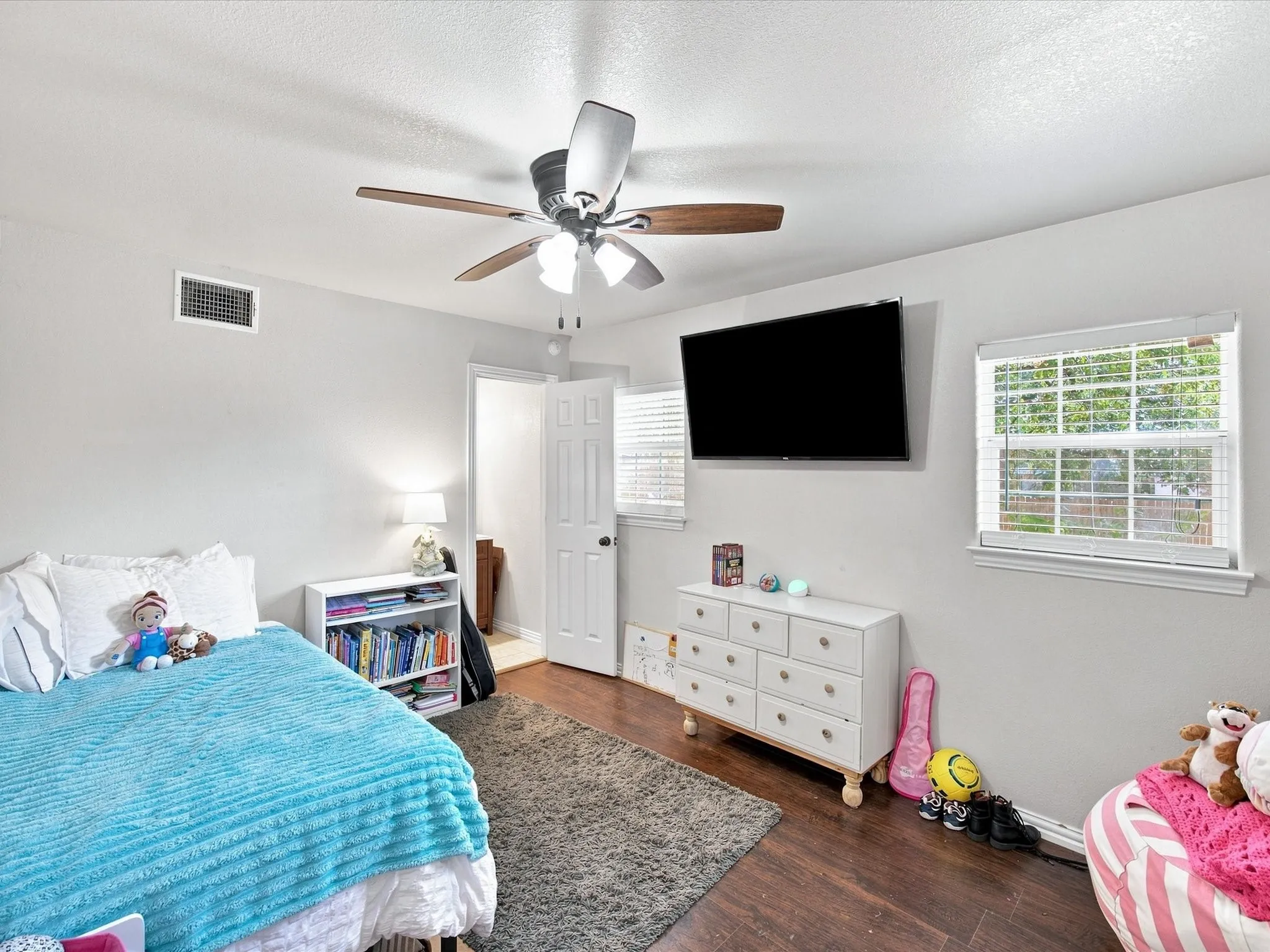 Wood-finish flooring, ceiling fan, white window blinds, and light gray wall paint