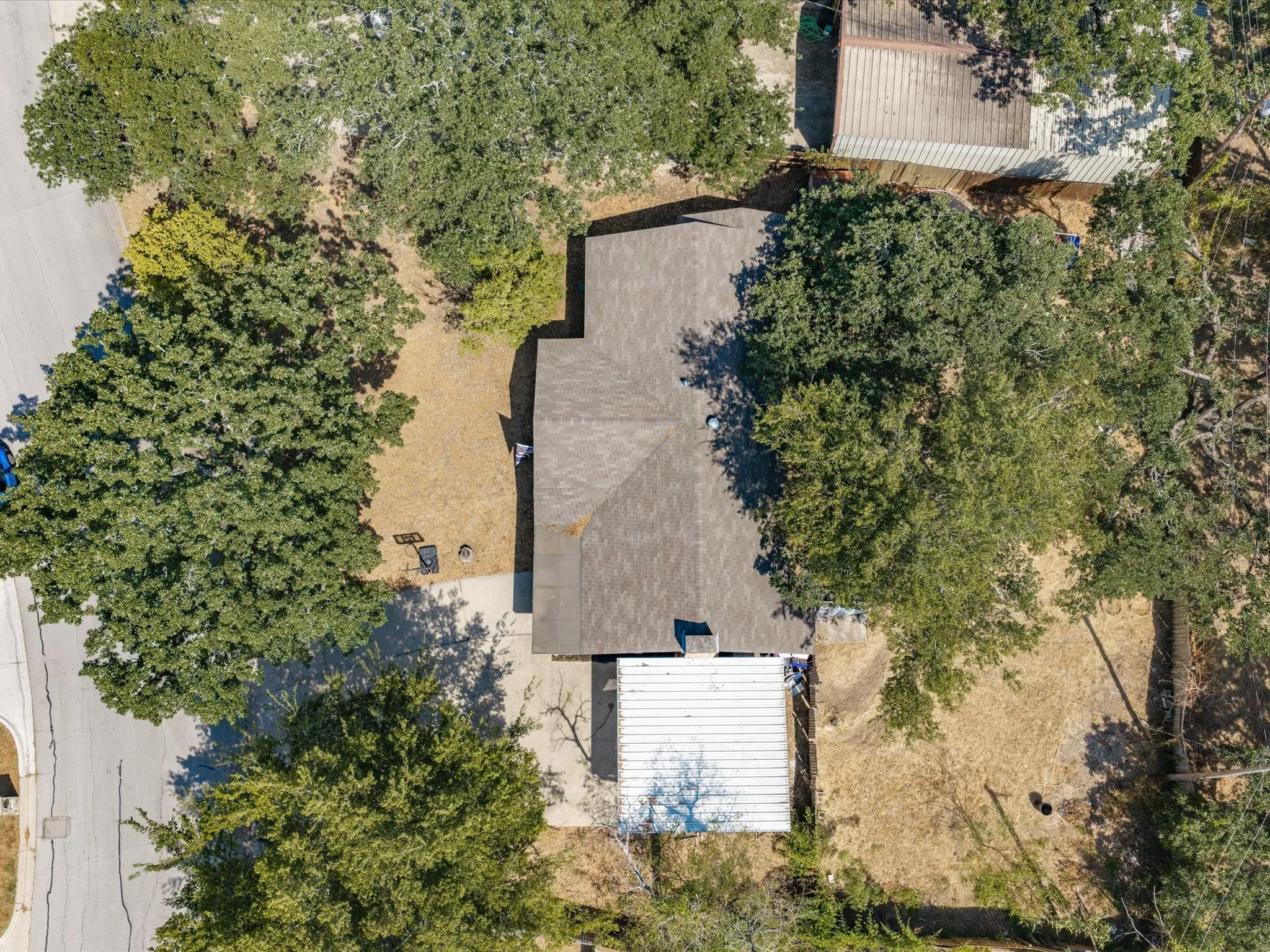 Property featuring a shingle roof, mature trees, and an attached covered structure