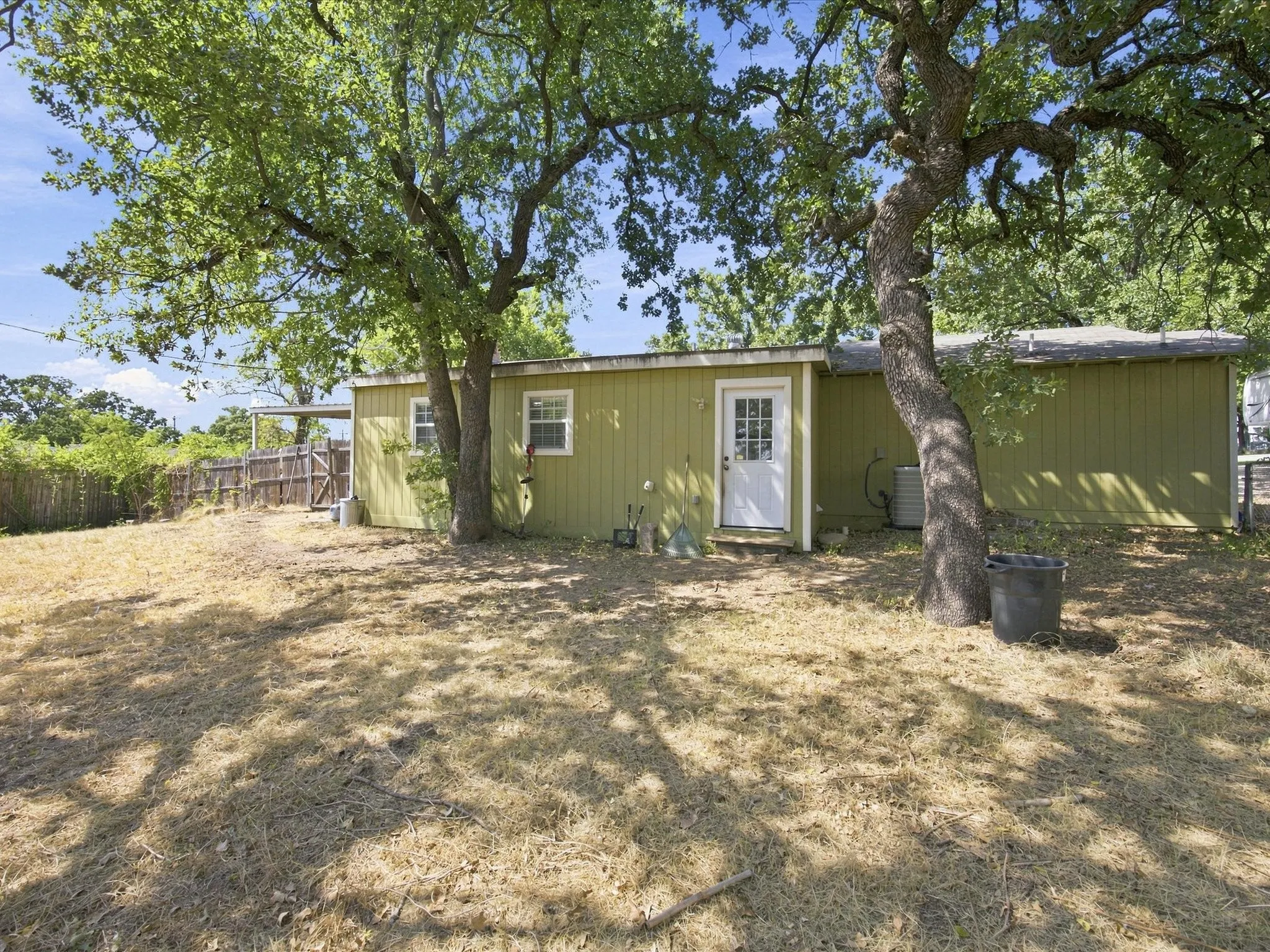 Rear exterior featuring vertical siding, a white paneled door, and two single-pane windows
