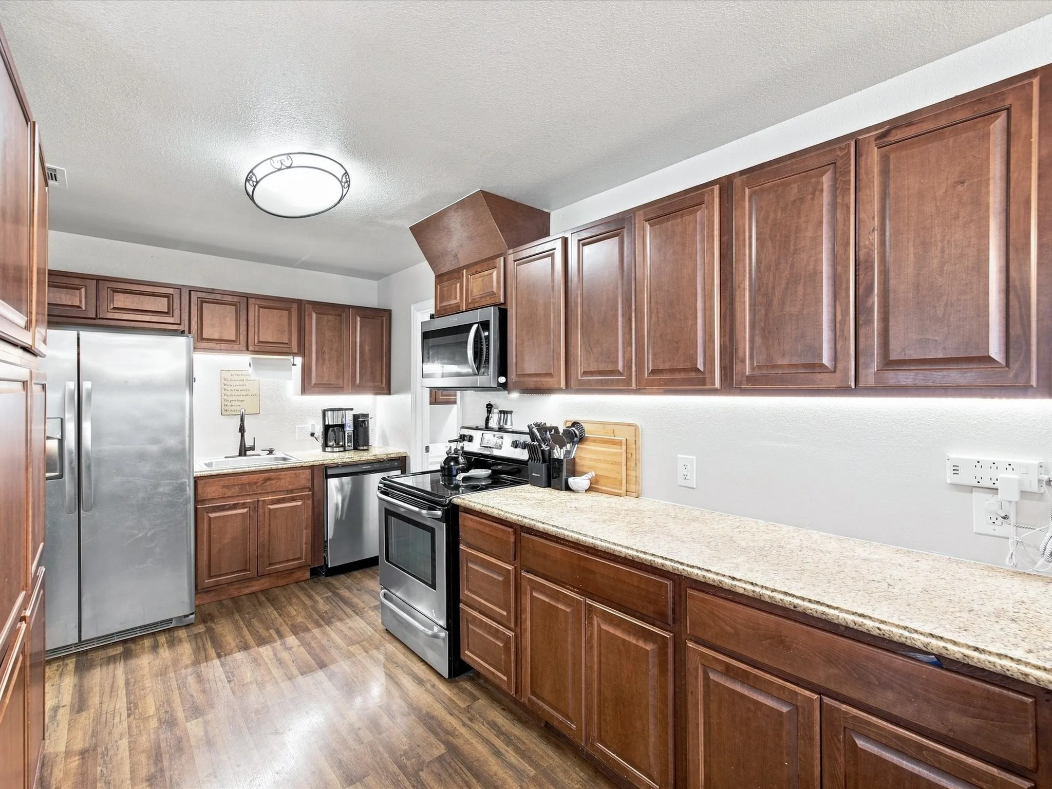 Kitchen with wood-finish flooring, wood cabinetry, and light-toned countertops