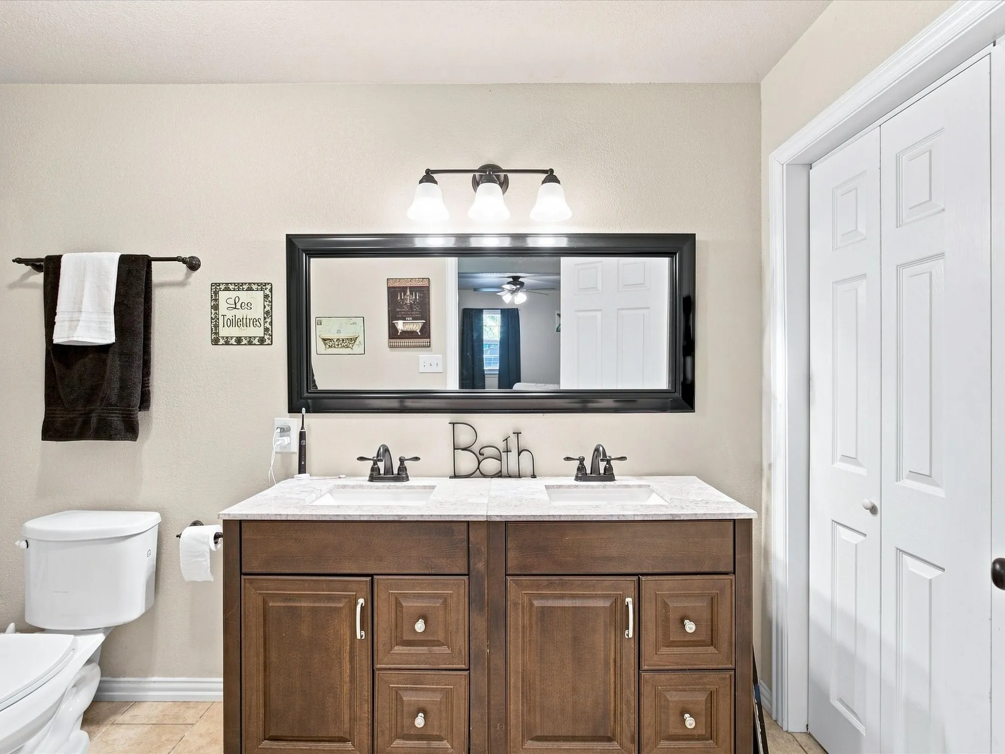 Double vanity with wood-finish cabinetry, white countertop, and dual sinks