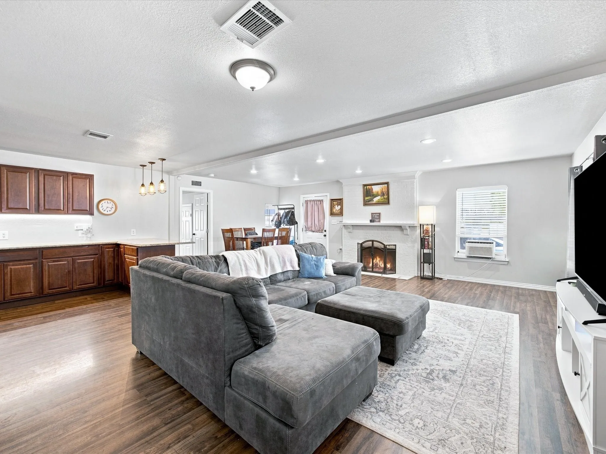 Open-concept living area with wood-finish flooring, a fireplace, recessed lighting, and a dining area