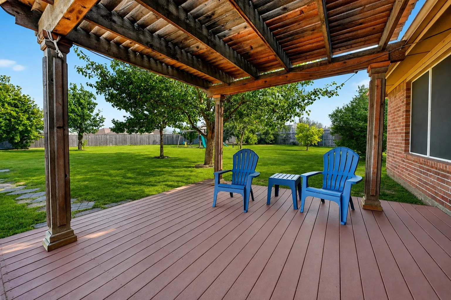 Spacious composite deck with wood-finish flooring beneath a sturdy timber pergola, offering generous covered outdoor entertaining space