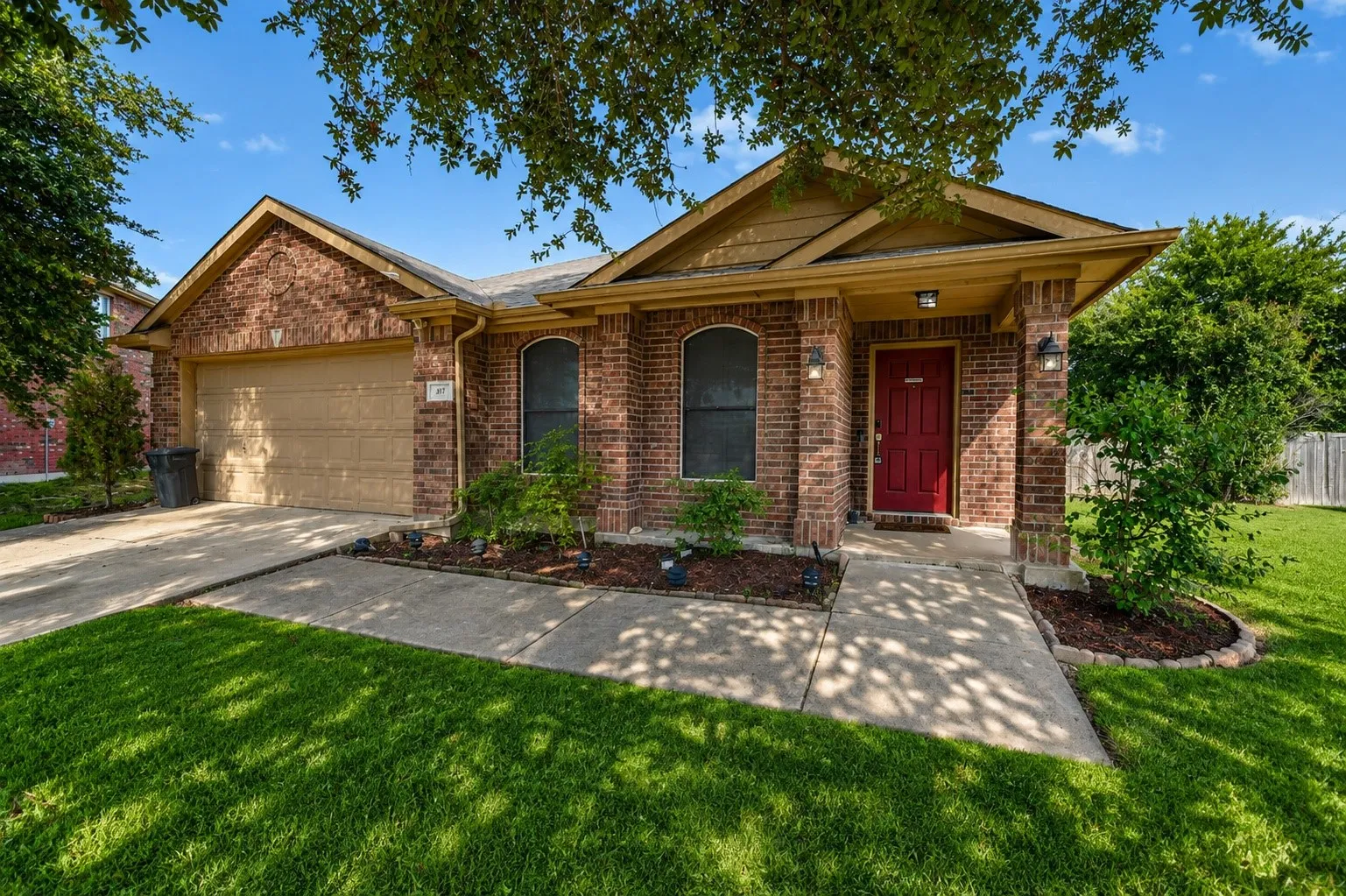 Charming brick residence featuring a welcoming front elevation with arched entryway, dual front-facing windows with dark frames, and a decorative pediment