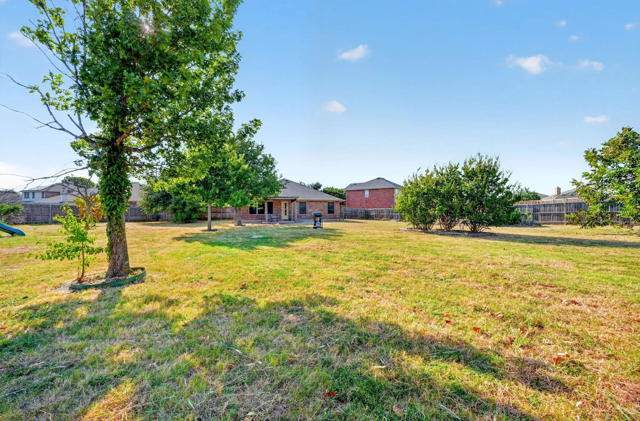 Expansive grounds featuring mature shade trees and open lawn space, with multiple residential structures including a brick home and outbuildings visible across the property