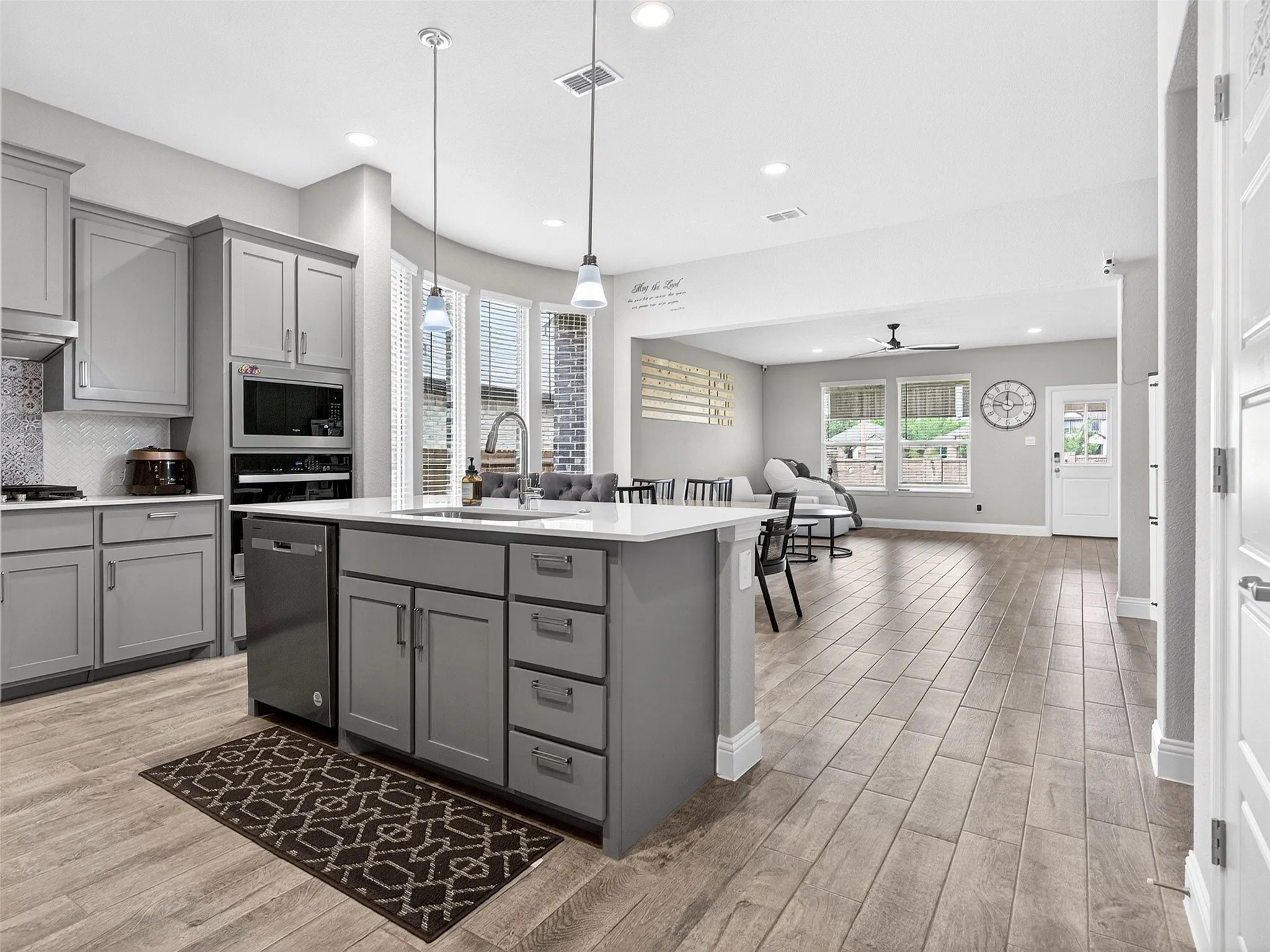 Open-concept kitchen and living area featuring wood-finish flooring, recessed lighting, and a kitchen island with pendant lighting