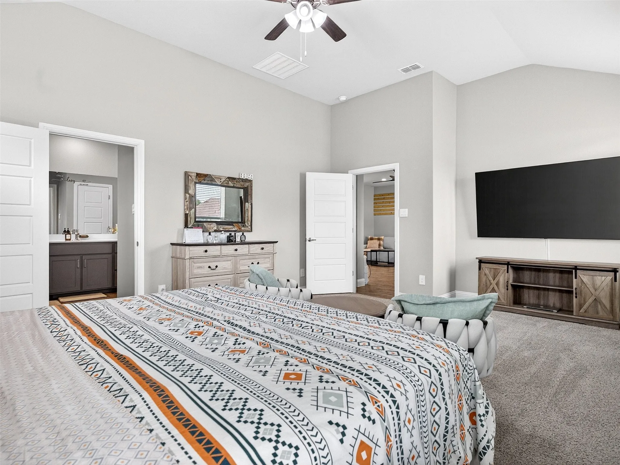 Vaulted ceiling with a ceiling fan, light gray wall paint, gray carpeting, and a built-in vanity with dark wood cabinetry