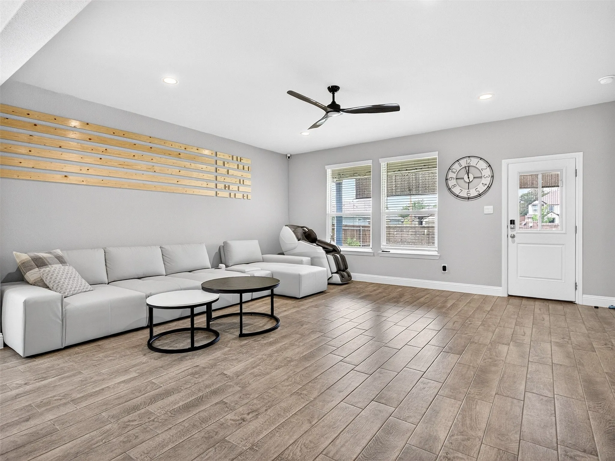 Wood-finish flooring, recessed lighting, ceiling fan, and multiple windows with blinds