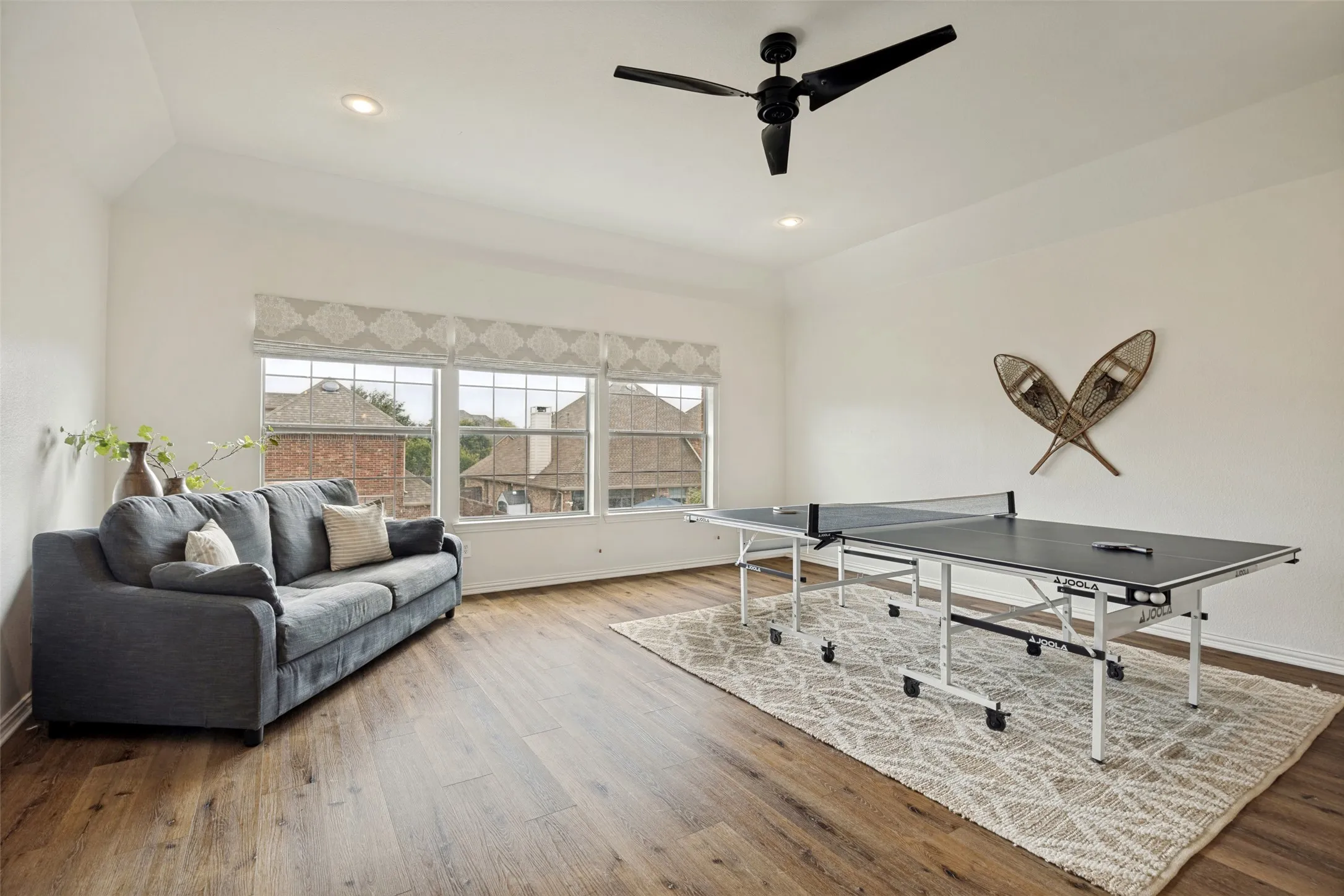 Vaulted ceiling with a ceiling fan, recessed lighting, wood-finish flooring, and multiple windows
