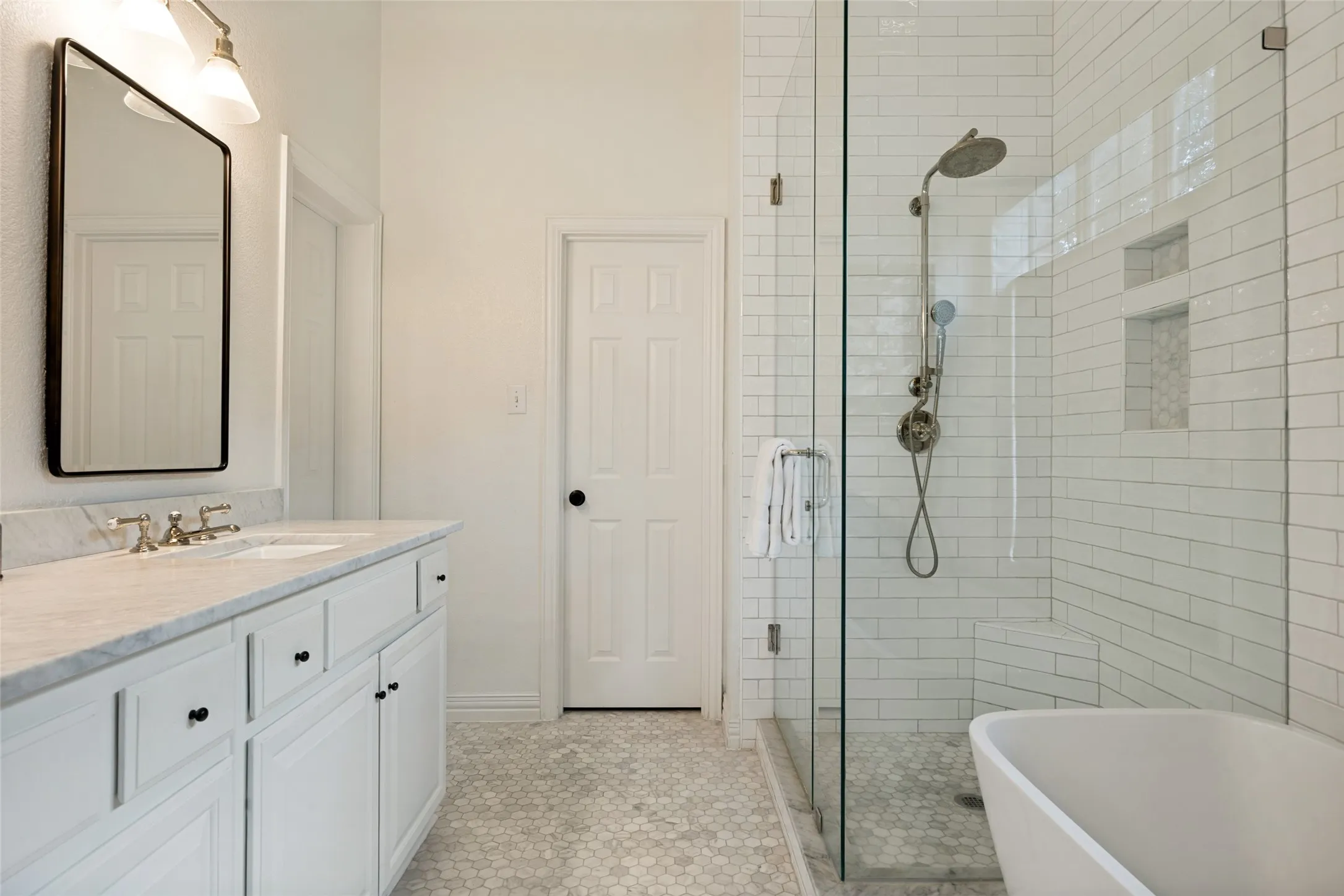 White shaker-style vanity with a light-colored countertop, undermount sink, and polished nickel faucet