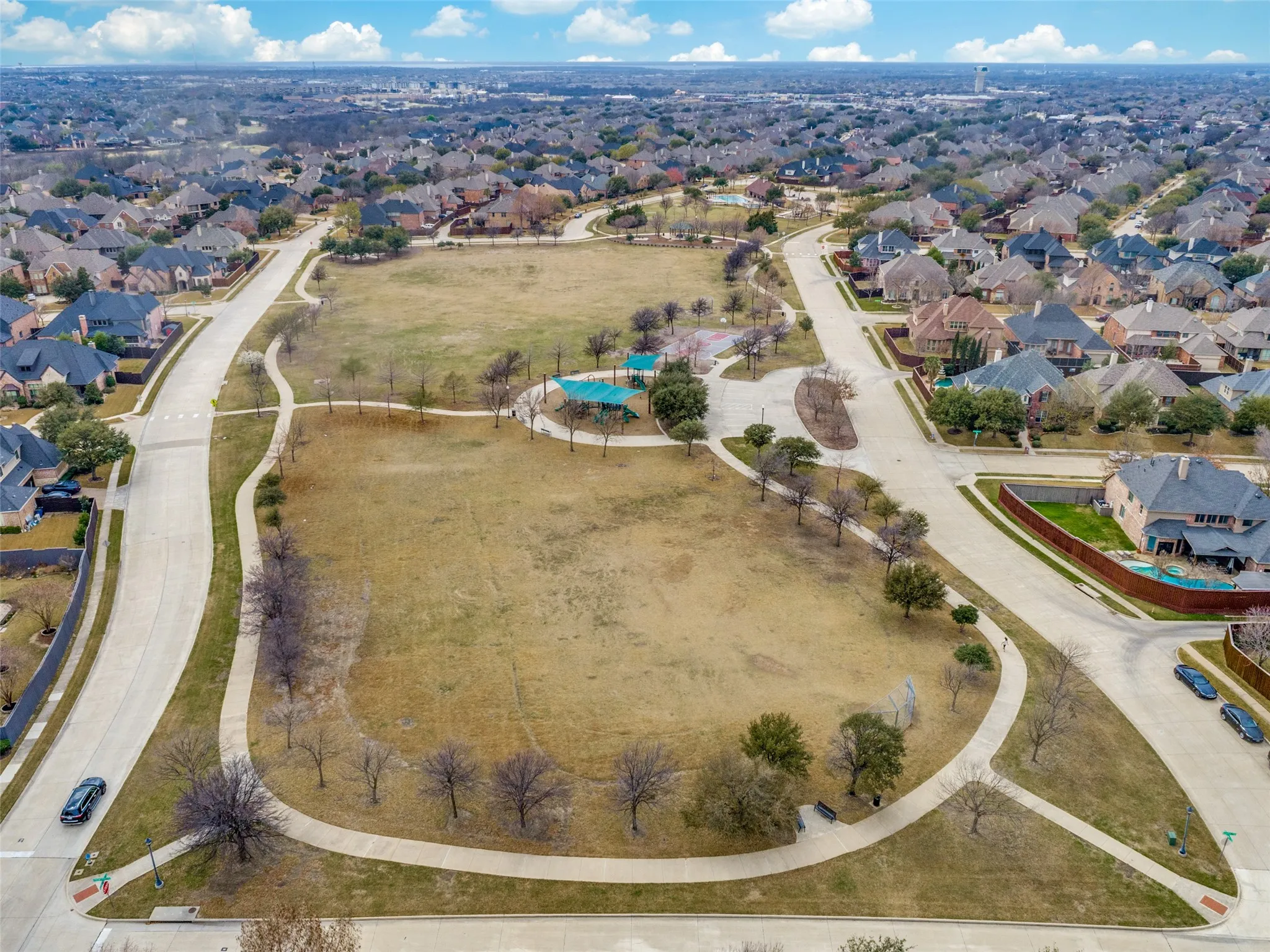 Expansive green spaces featuring walking paths, mature trees, and a residential community backdrop