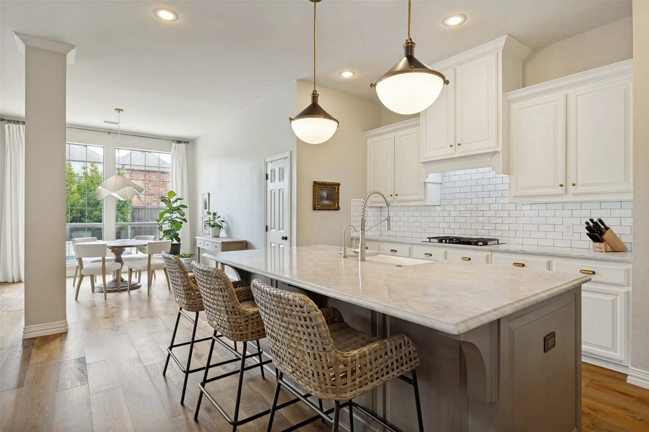 Kitchen island with a light-toned countertop, white cabinetry with brass hardware, and a white subway tile backsplash