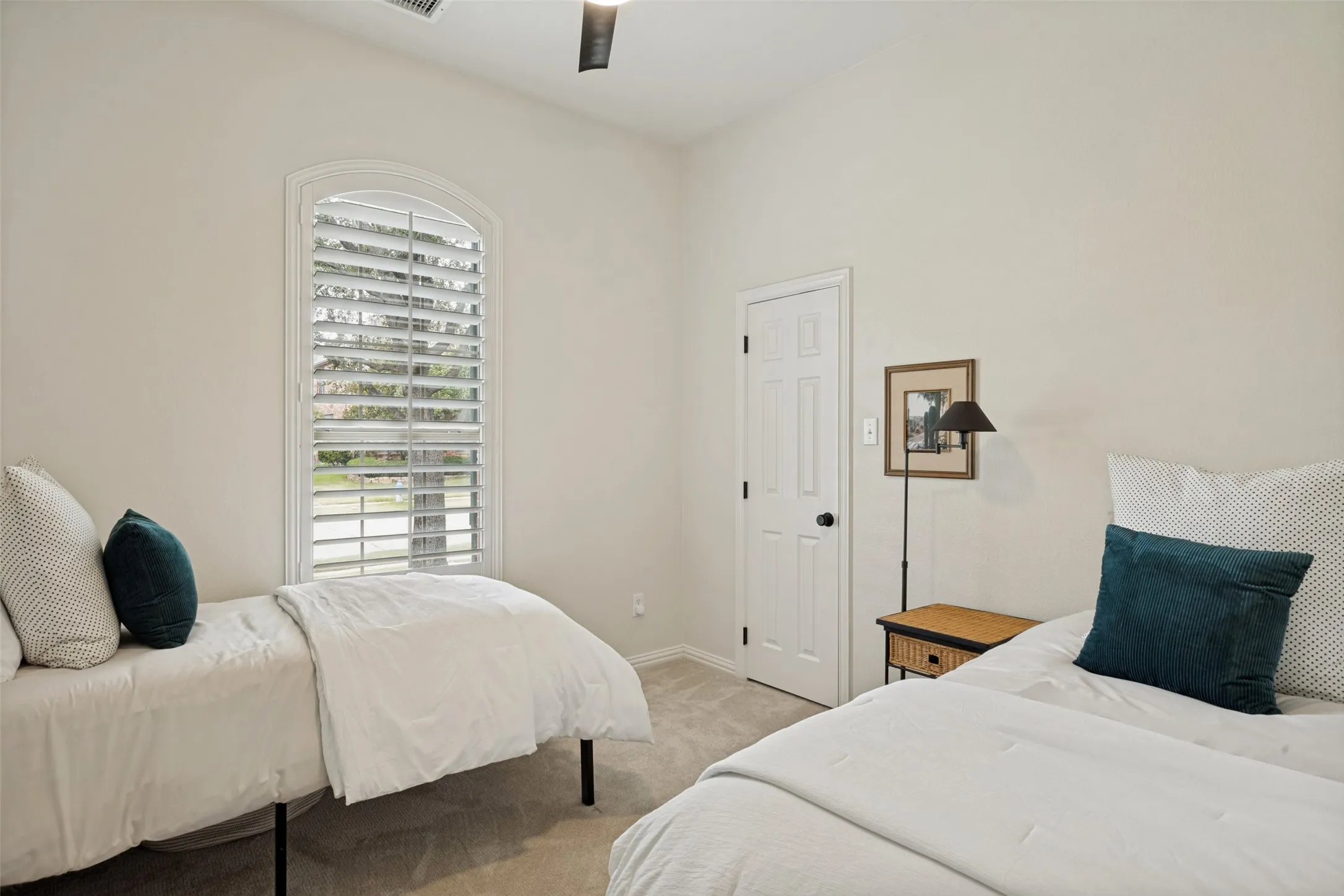 Arched window with plantation shutters, vaulted ceiling, ceiling fan, neutral wall tones, and carpet flooring